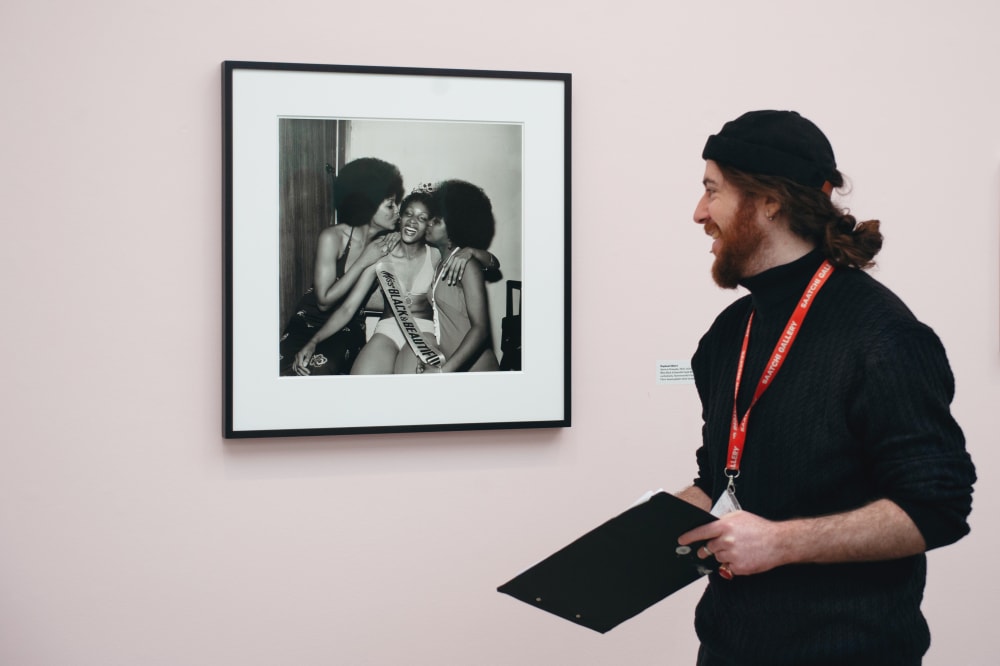 Karl looking at one of the photos on display; a black and white photo of 3 women smiling.
