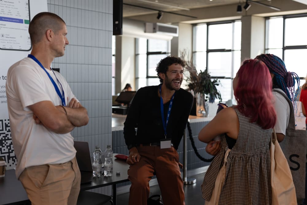 Students speaks to 2 employers across a table, with the Dweet brand banner in the background