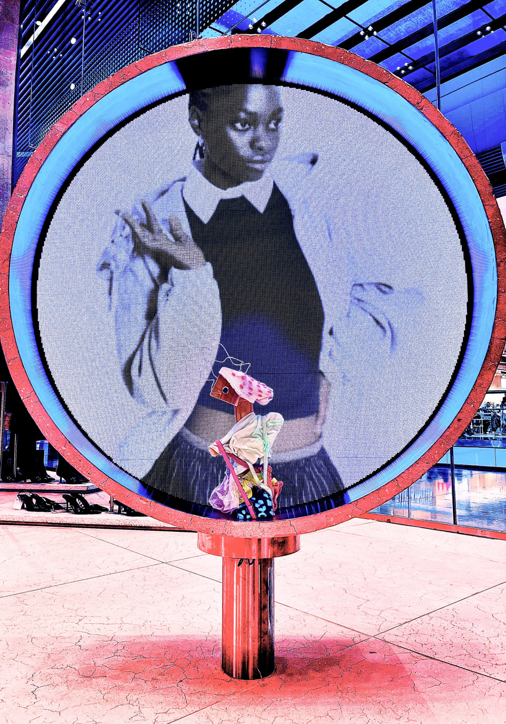 An effigy placed against a round digital screen in a fashion store.