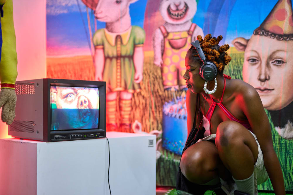 Visitor at the Summer Shows kneeling down to watch a video on an old TV with headphones plugged in.