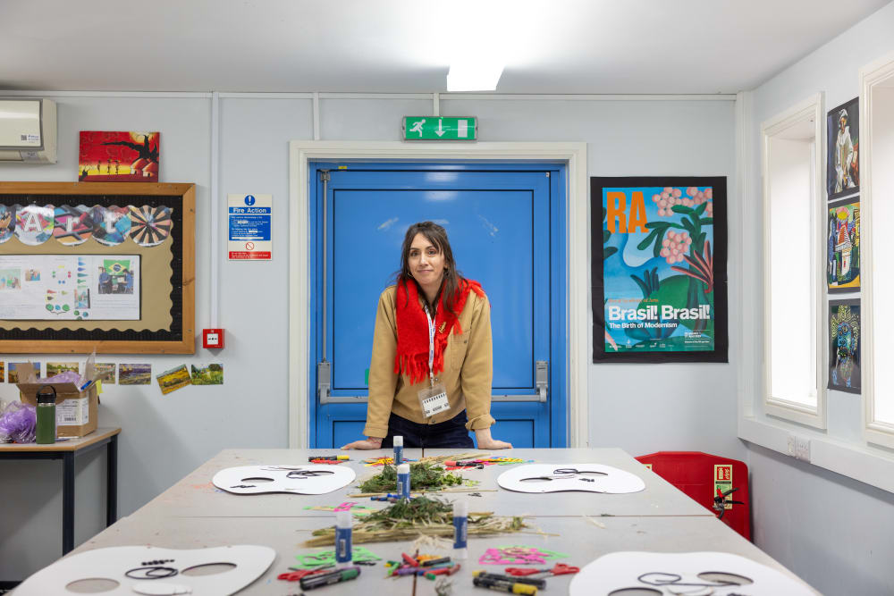 A women standing at the head of a table in a primary school classroom.