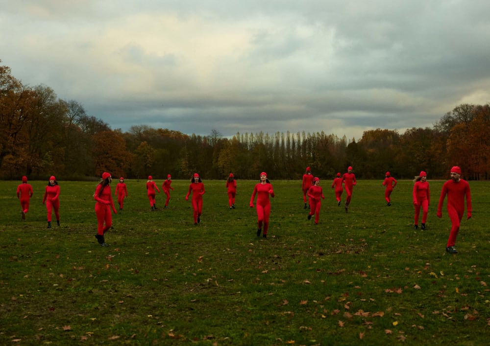 An image of multiple people wearing all read in a green field of grass