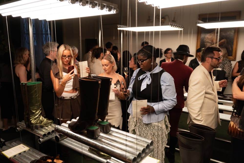 Boots in glass case, with spectators looking in. 