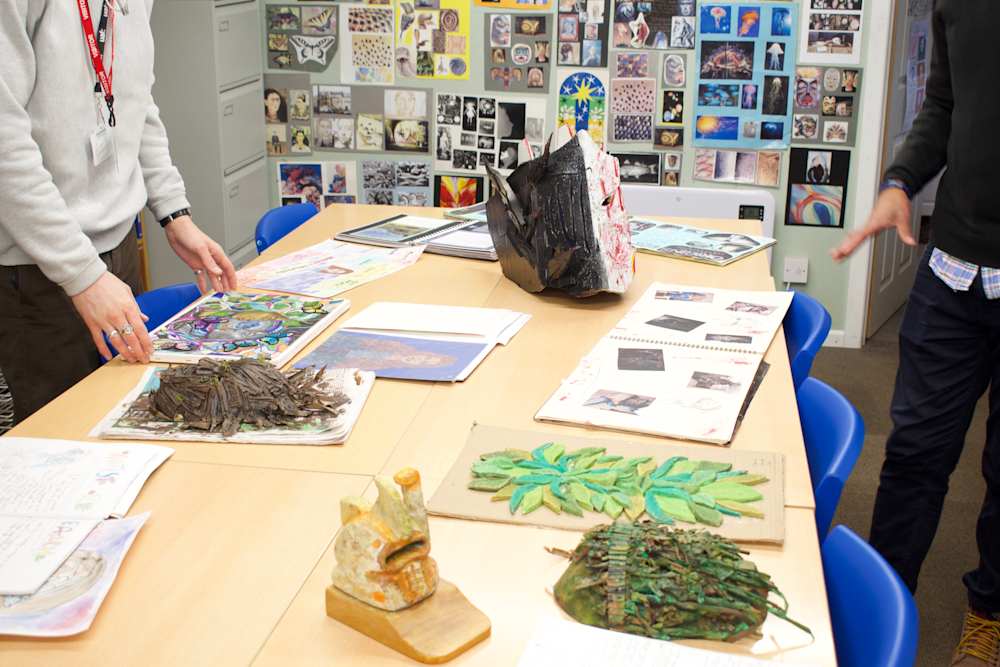 Art classroom with student works on table. 