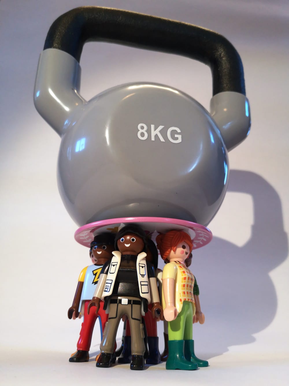 Small Playmobil figures with an 8KG weight balanced on their heads