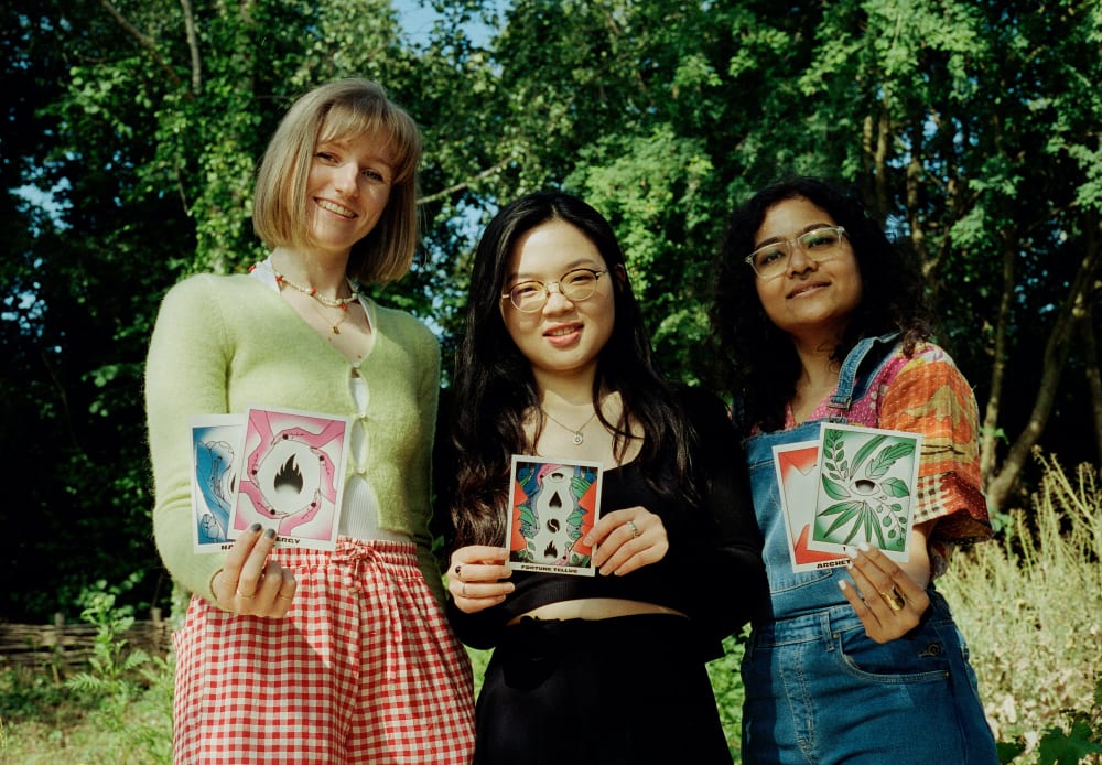 Students standing in a meadow, holding up colourful illustrations