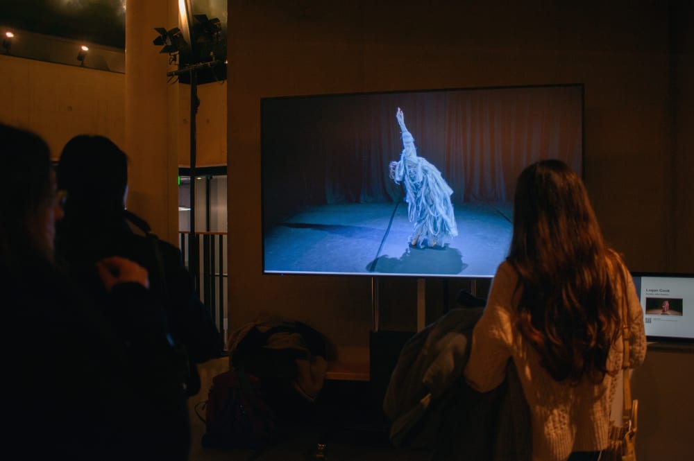 Guests watching student work on a screen in the foyer