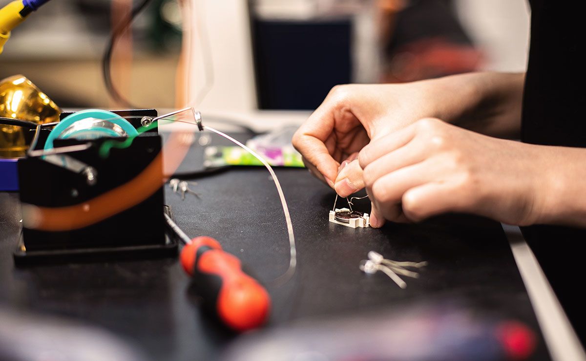 A student uses the soldering bench to work on her project.