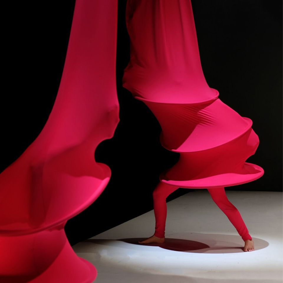 Two performers dance in red costumes on a stage