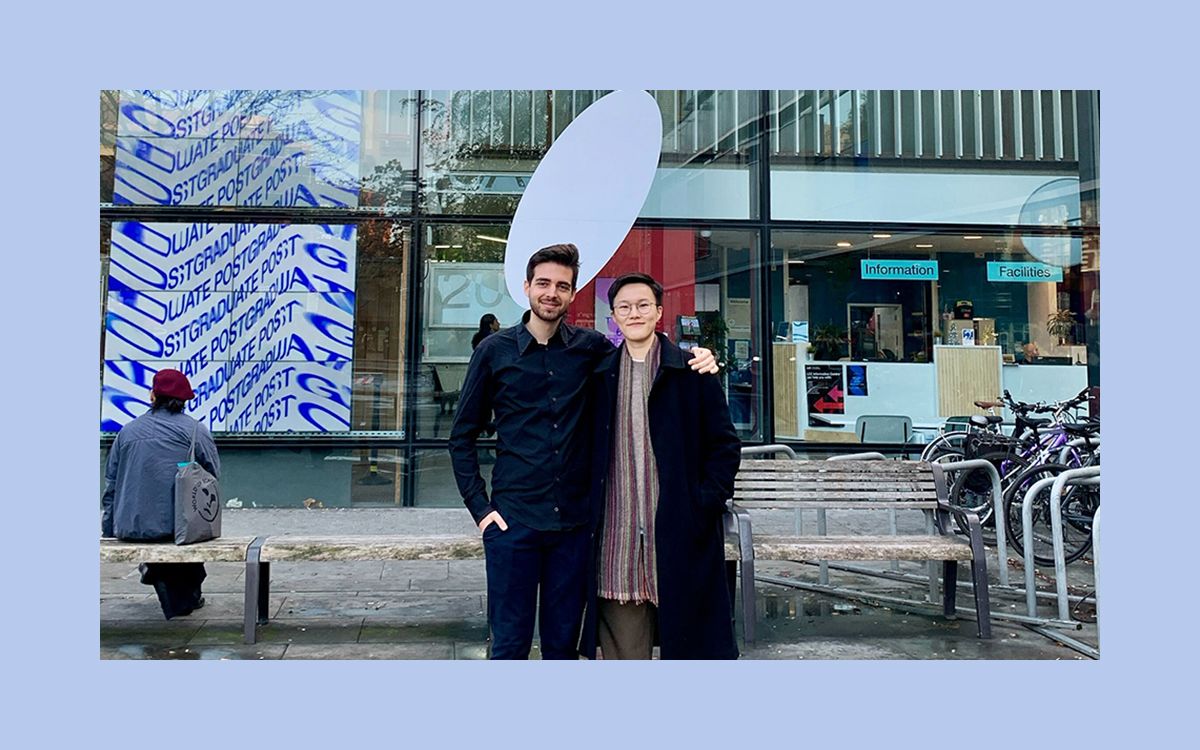 Two people stand outside an art exhibition.