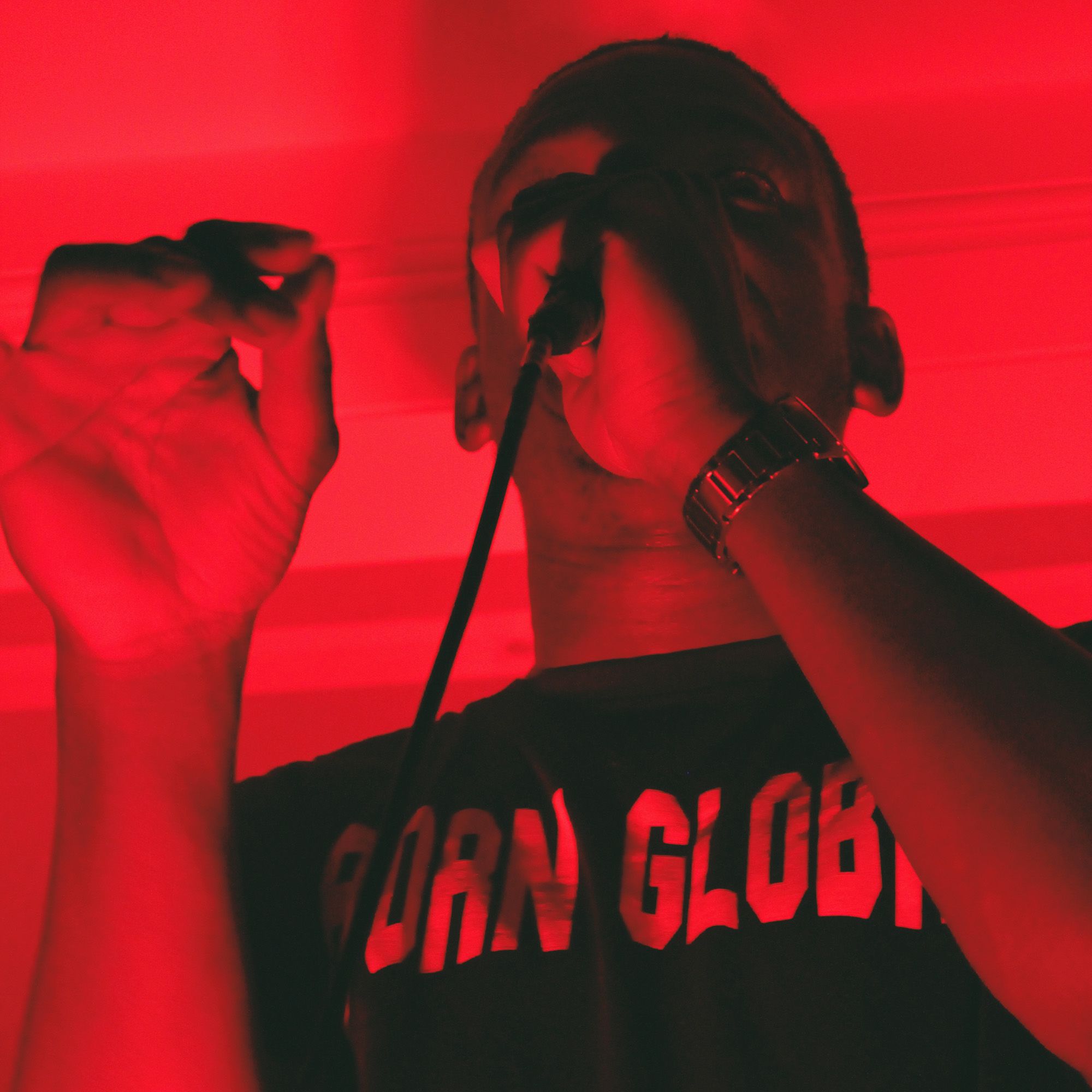 Close up of a student singing into a mic, lit in red wash.