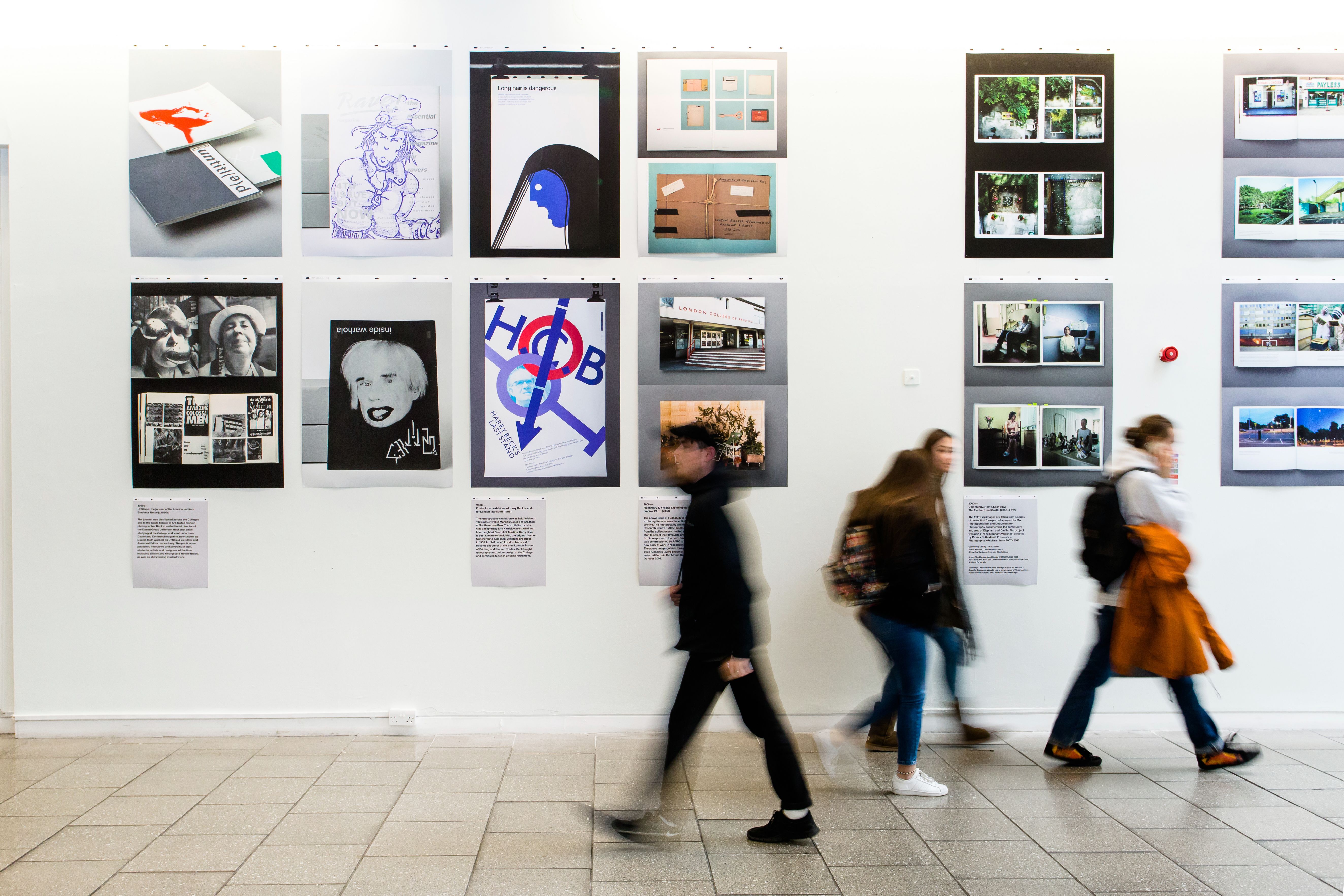 People walking past an exhibition wall, with their movement blurred.