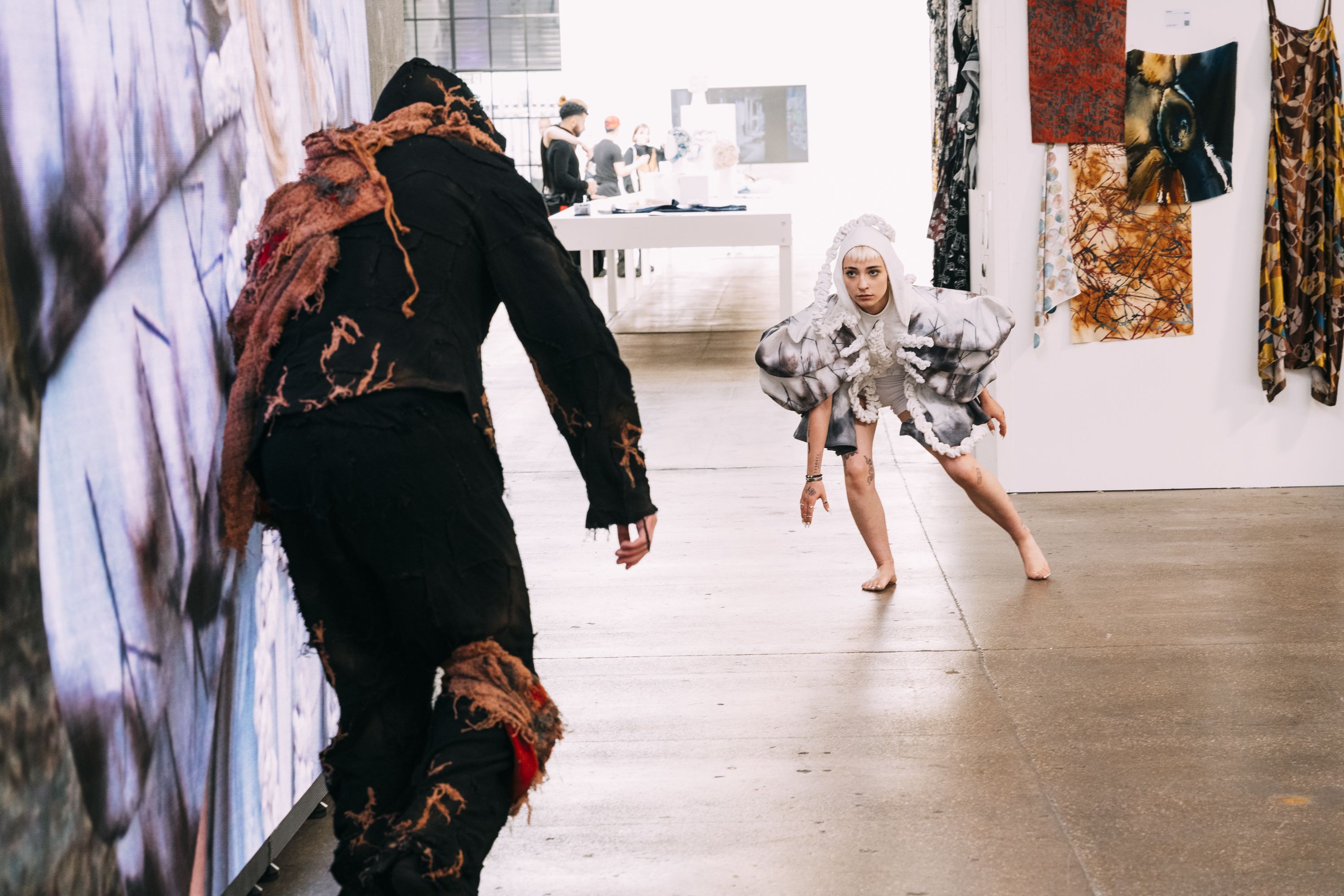 Woman wearing costume crouching and man wearing black costume shown from behind during performance