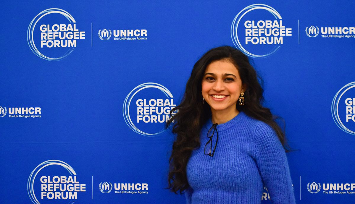 A person smiles in front of a blue background.