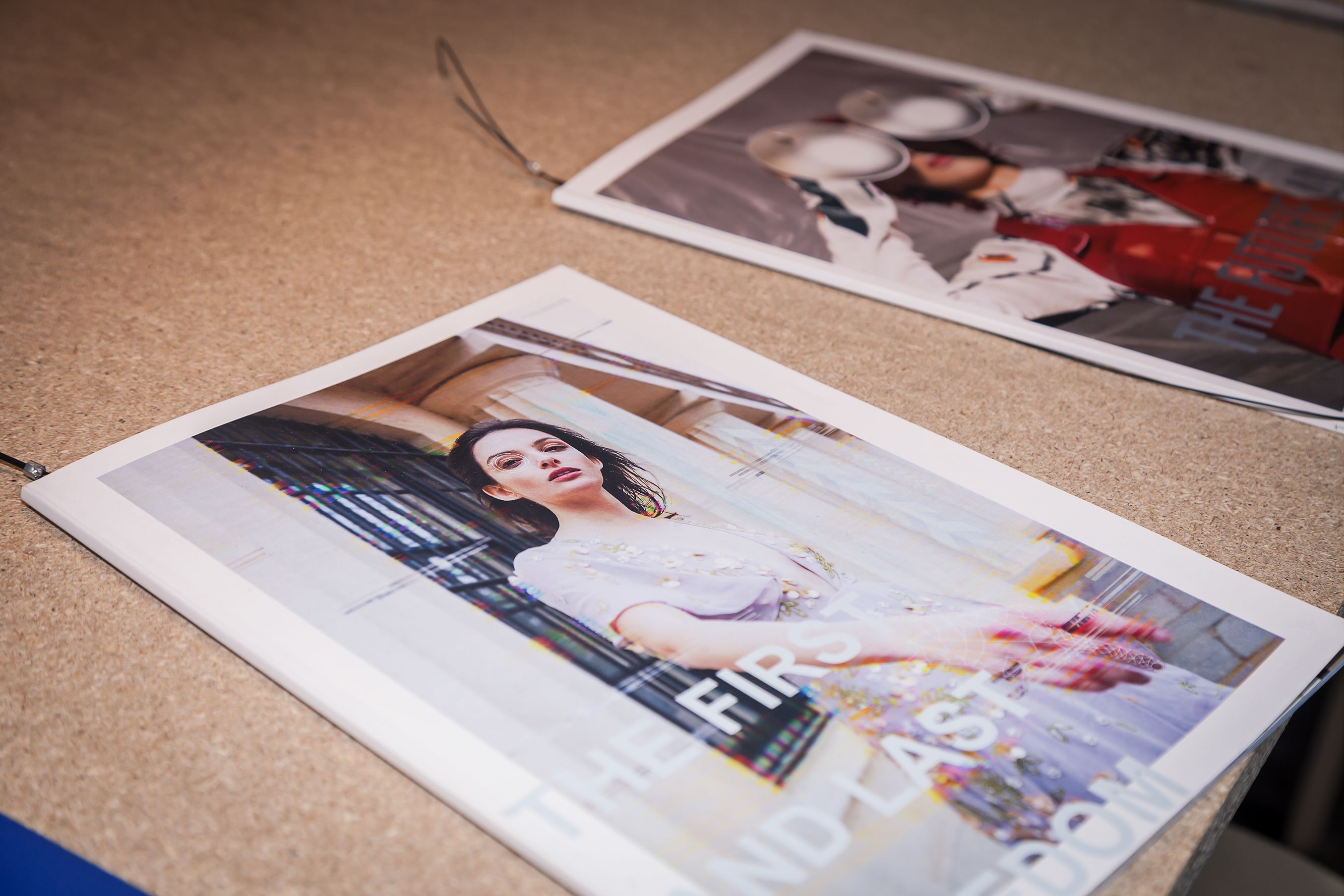 Fashion magazines attached to a cork board.