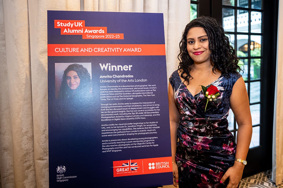 A person smiles beside an information board at an awards ceremony.
