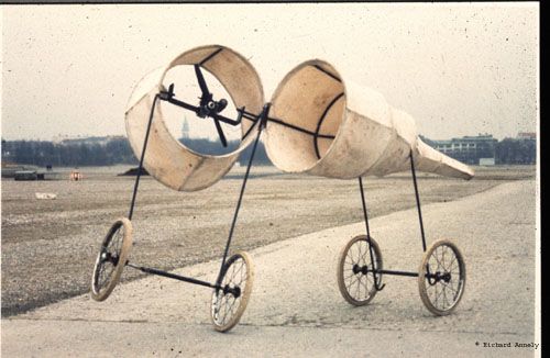 A sepia photo of 2 large, lightweight cones on a wheels leaning against each other 