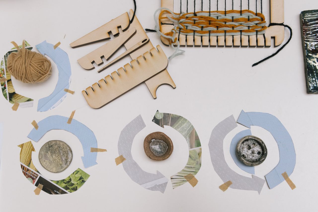 3 cut out paper and materials making renewable arrow signs, with wool and yarn equipment lying next to it