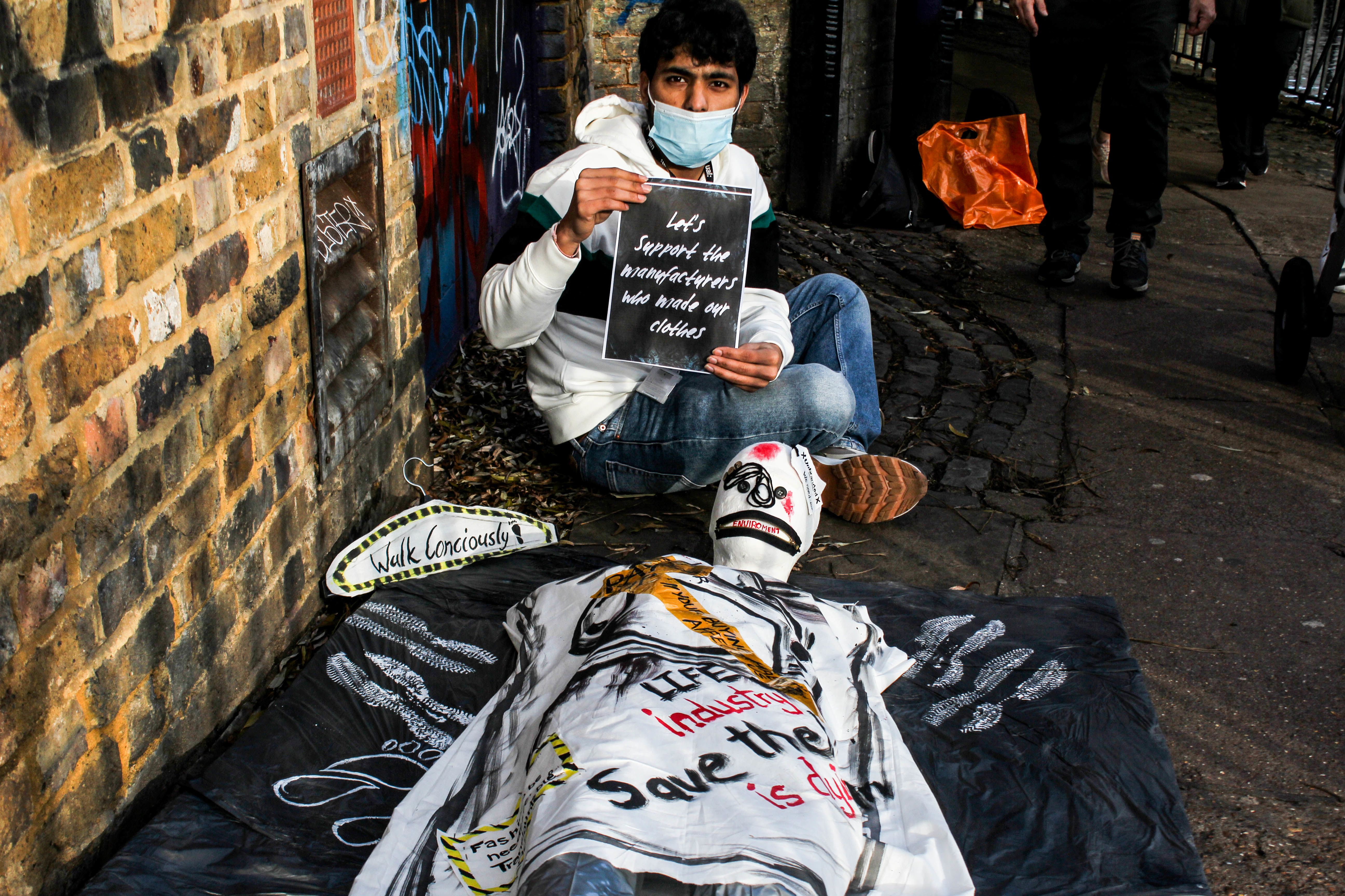 sculpture of a mummy on floor with handwritten notices and stickers about fashion