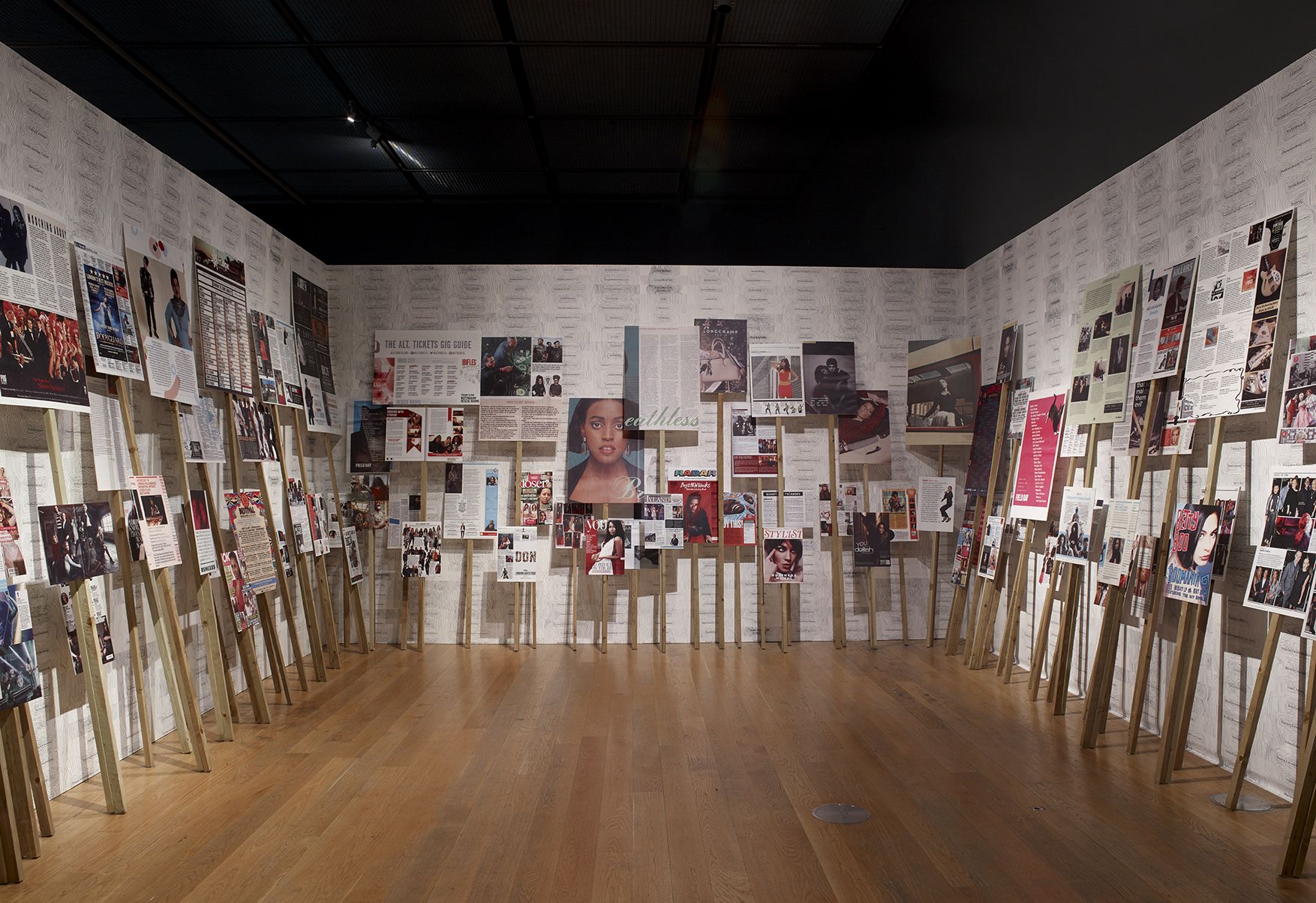 3 walls of an indoor installation of placards with images mounted on sticks of different heights