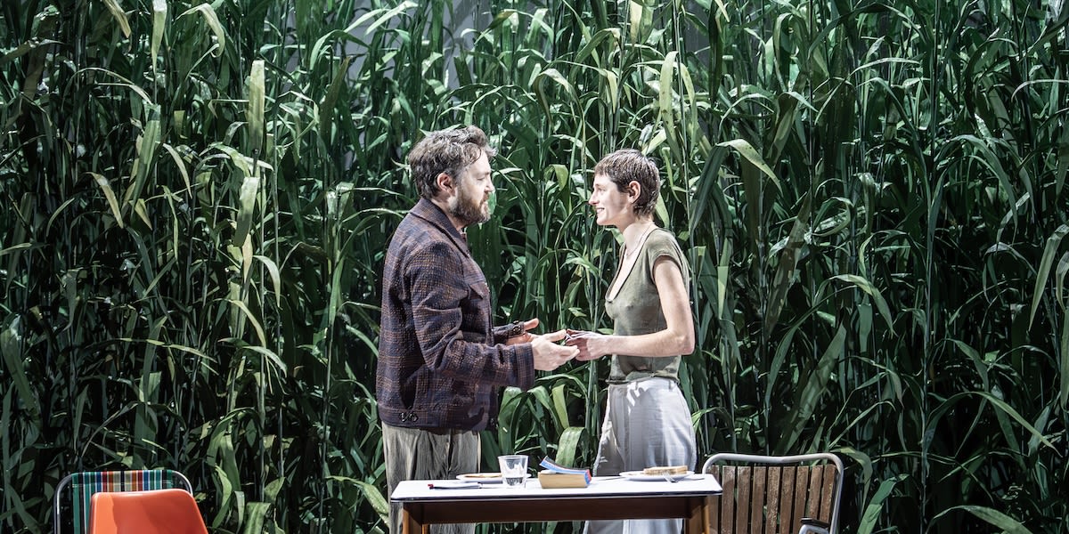 Two people standing in front of a corn field 