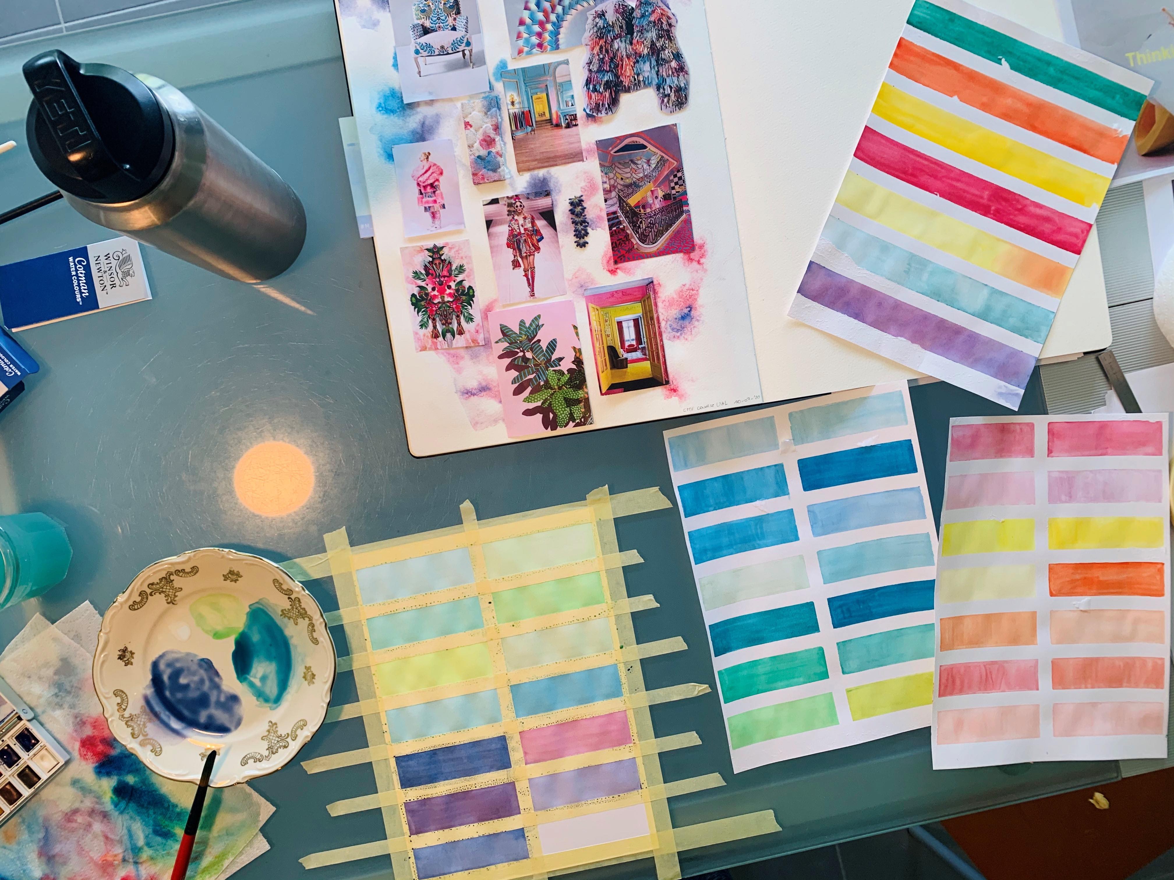 A photo of a desk with paint swatches and sketchbooks