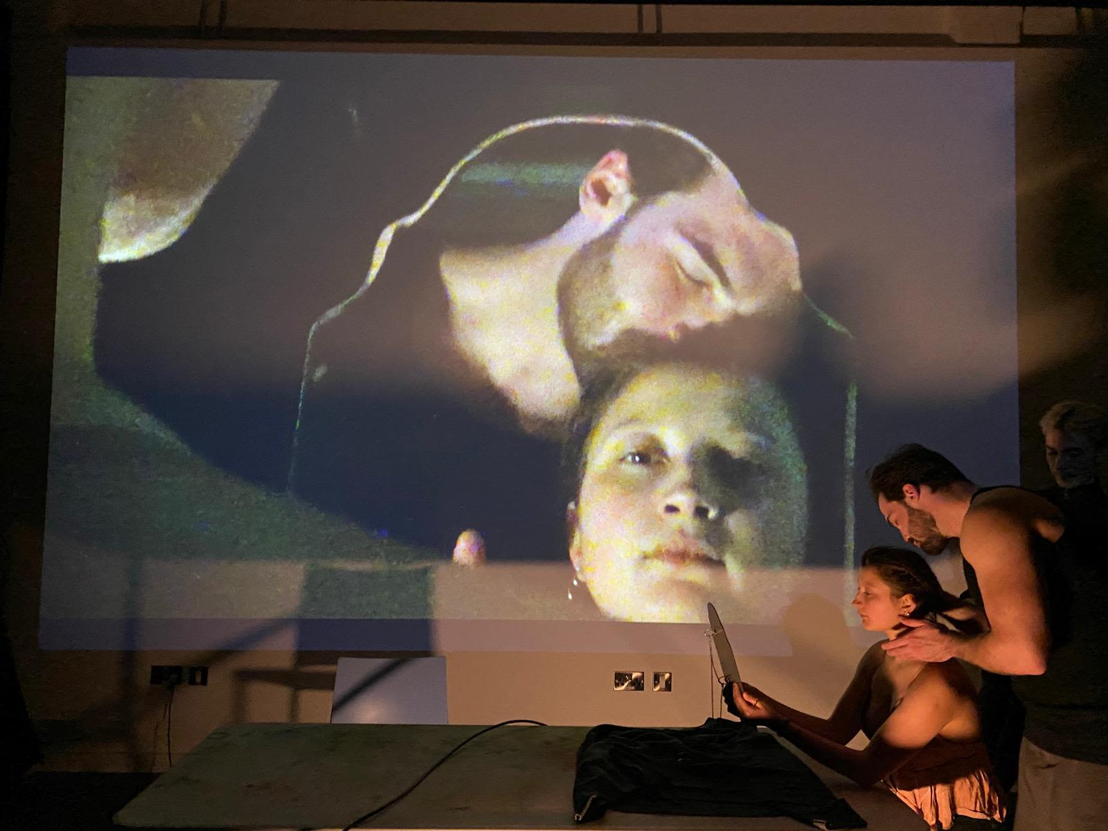 a live scene shot from the production performance capturing two actors on stage with a projected visual of them in background