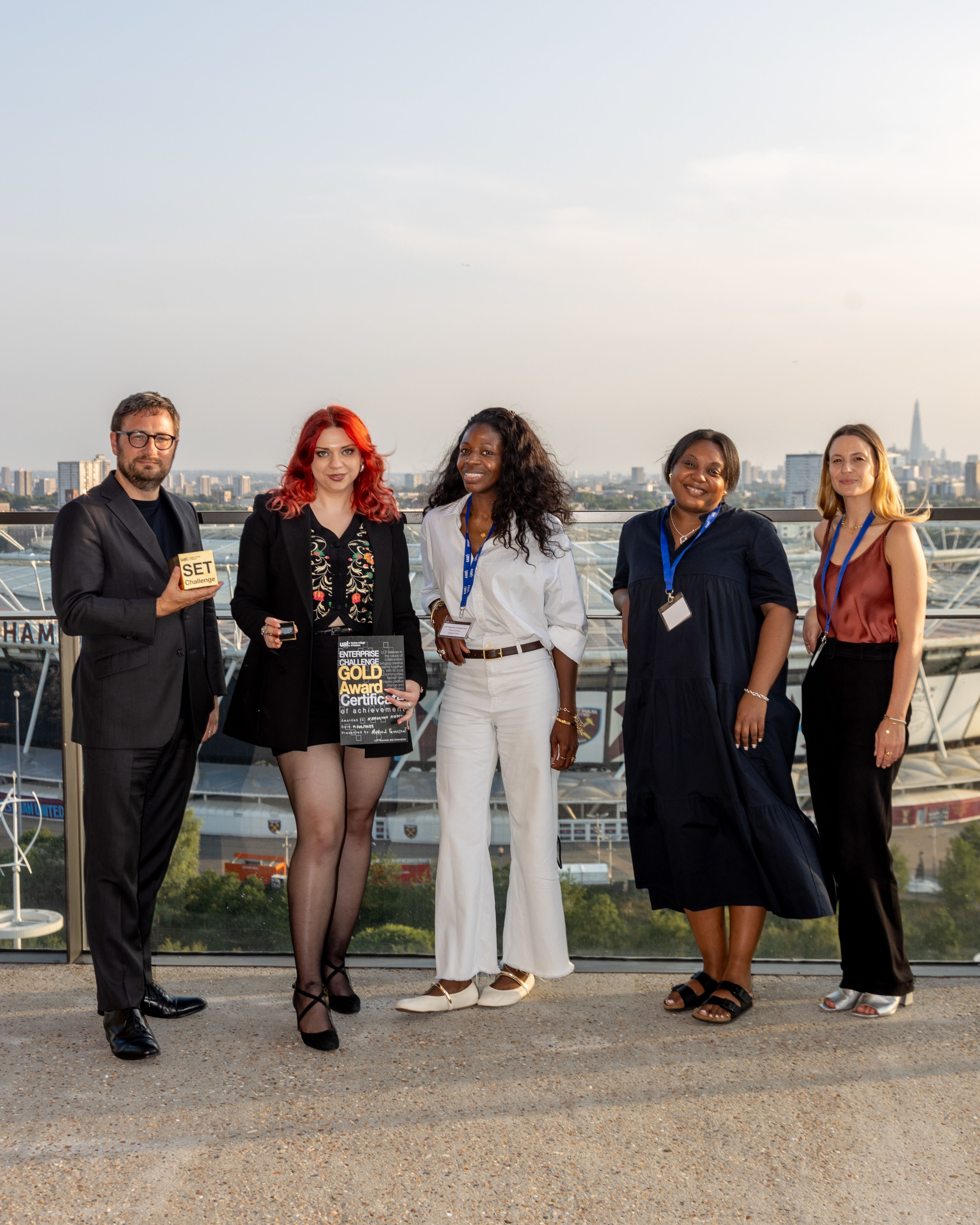 5 people standing on a balcony overlooking London. 