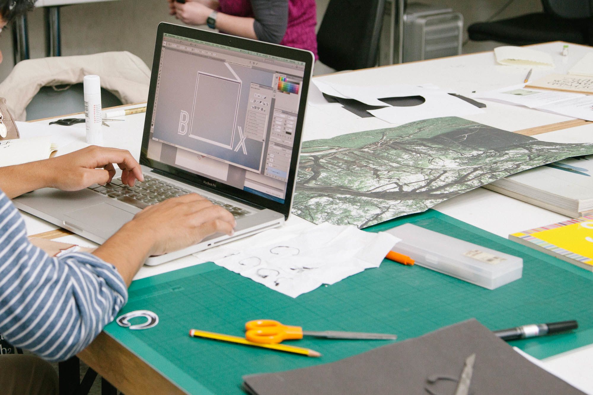 Student navigating Photoshop on a laptop
