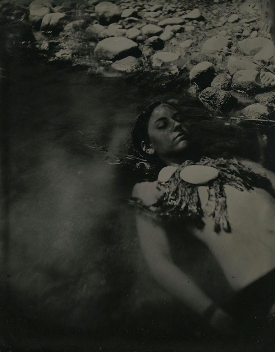 a photograph of the artist in water covered in seaweed