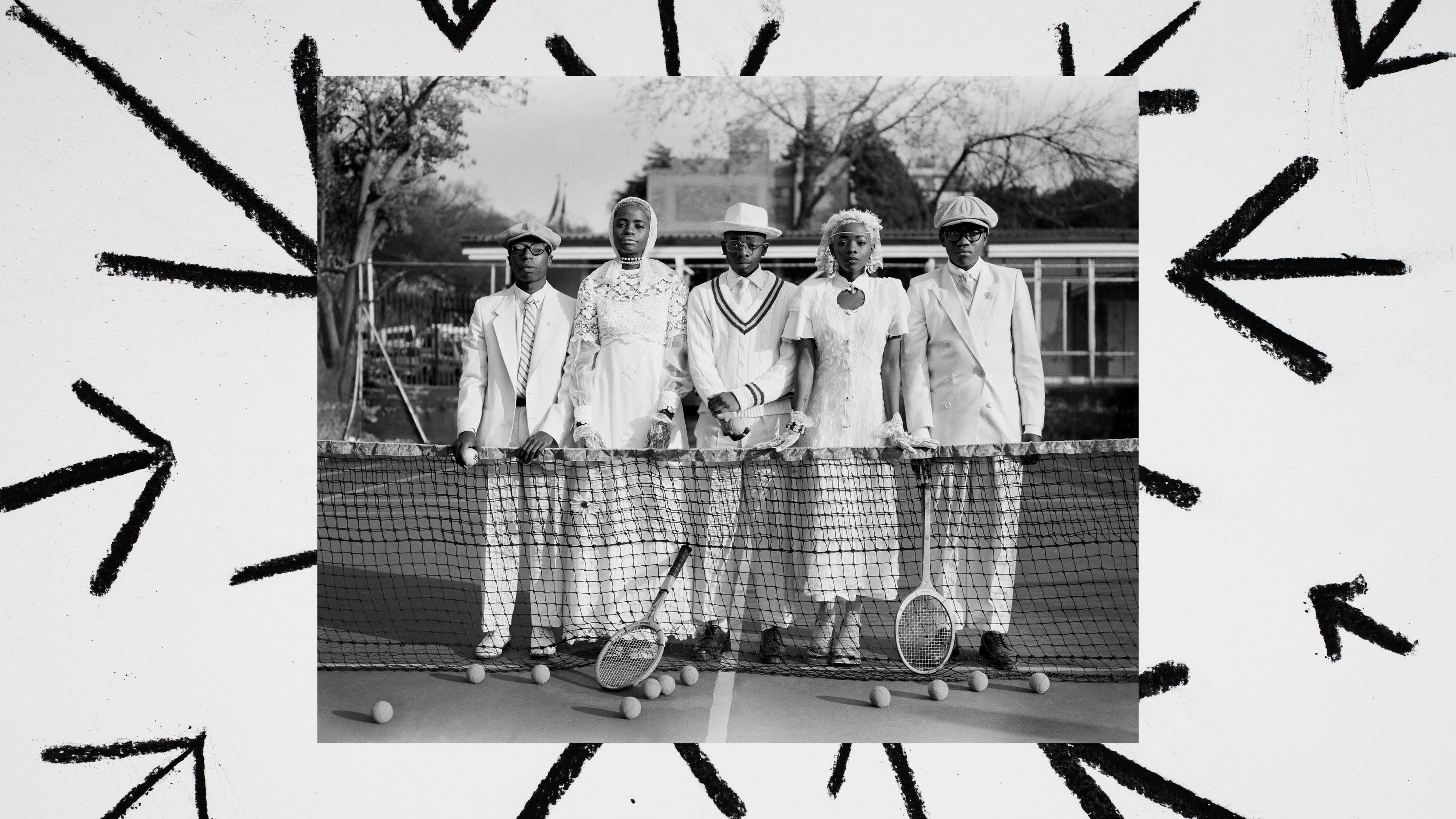 A black & white photo of a group of tennis players in tennis whites in front of a tennis net. The photo has a border with a white background and black charcoal arrows