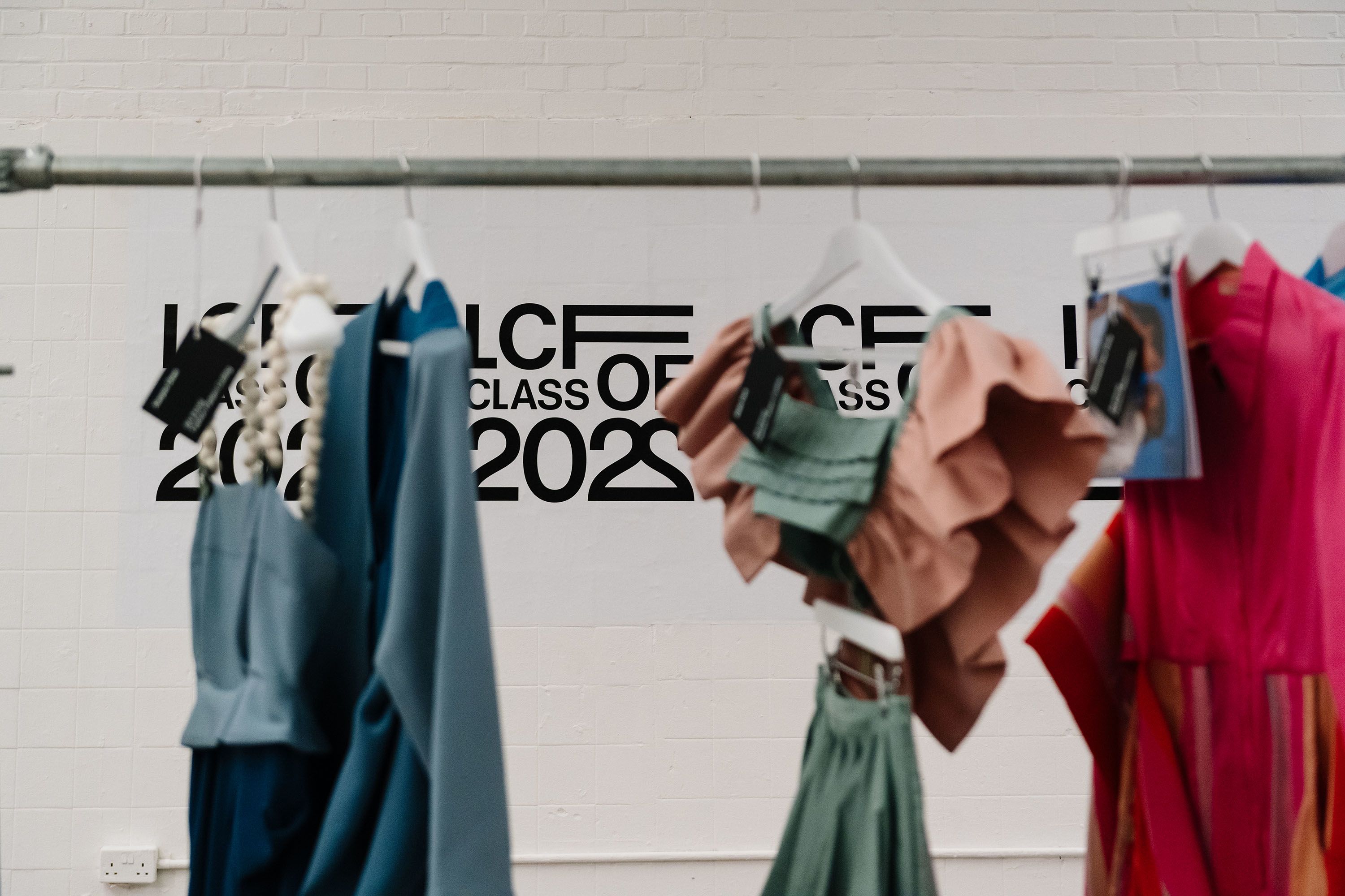 LCF Class of 2022 logo in background with defocused garments on rail
