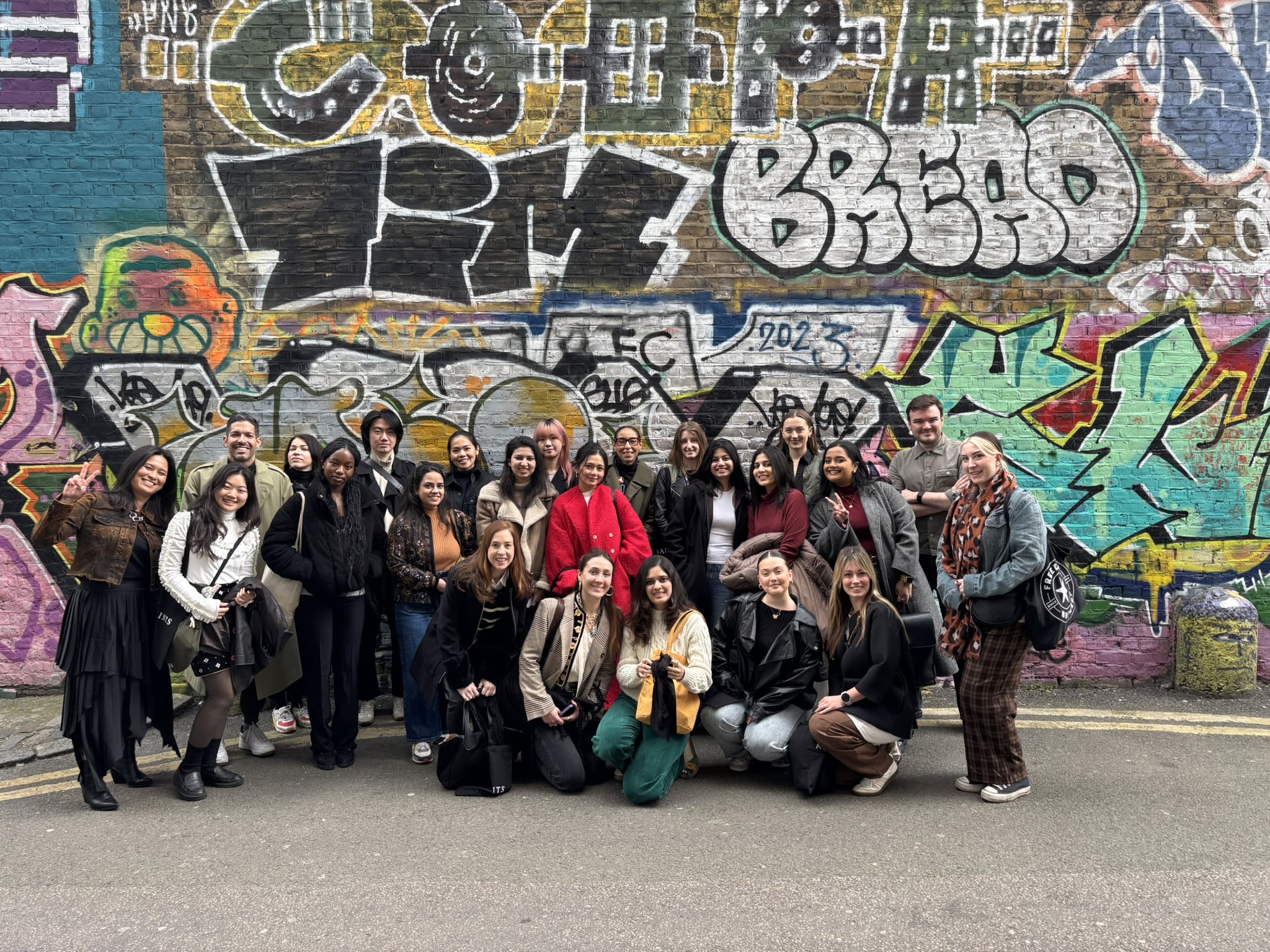Student pose for a group photo in front of a graffiti wall