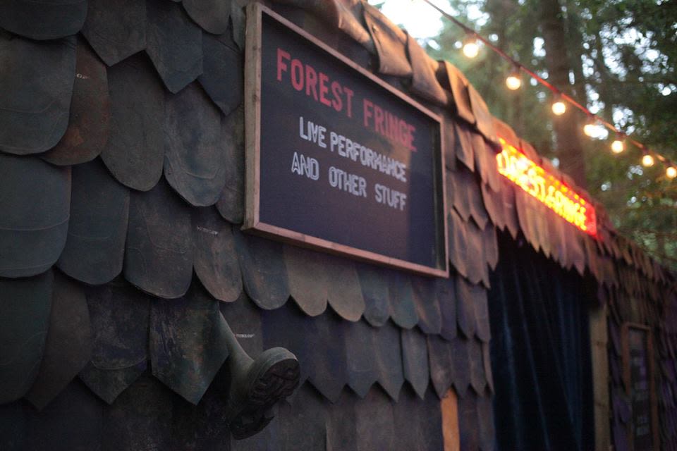 a building in a woodland area, with a sign attached to the outside which reads 'forest fringe'