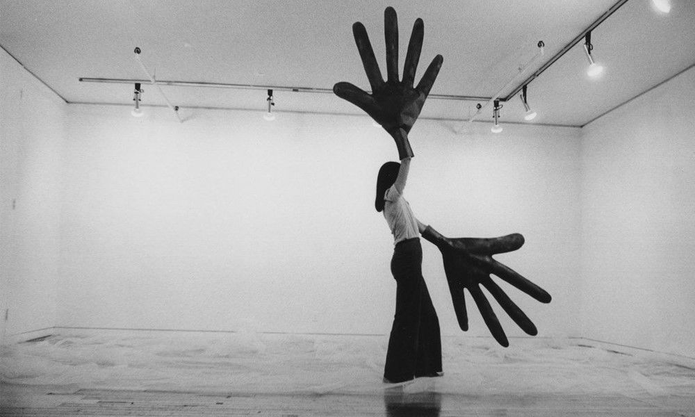 woman with sculptural oversized hands in gallery space