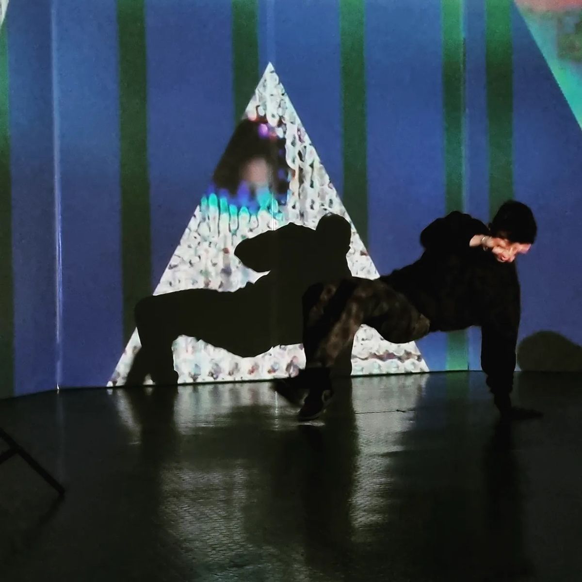 Performers are silhouetted against a giant projection map of light.