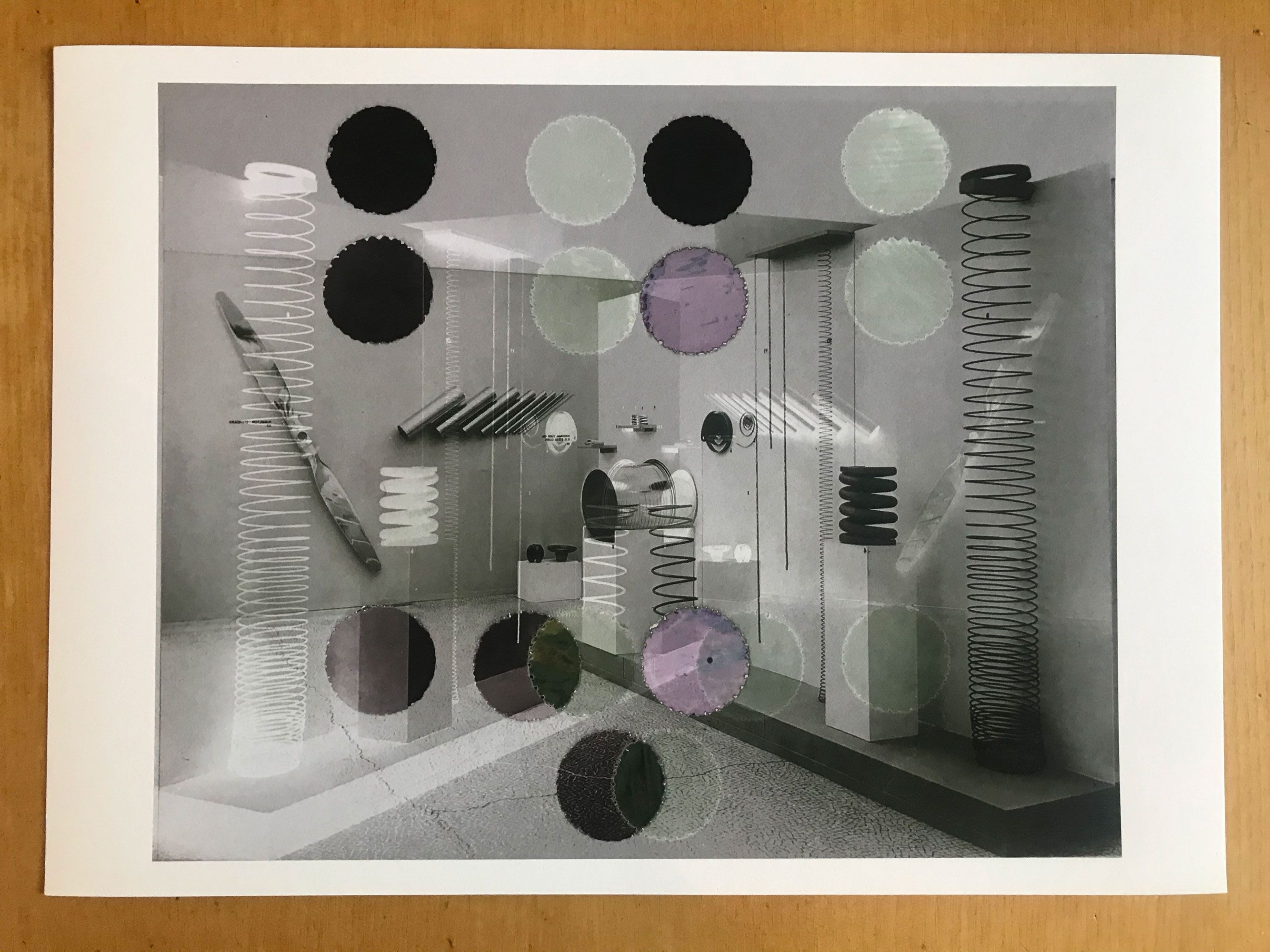 A print on a table. The image on the print is a back and white abstract including plinths and springs overlaid with black, white and pale lilac circles.