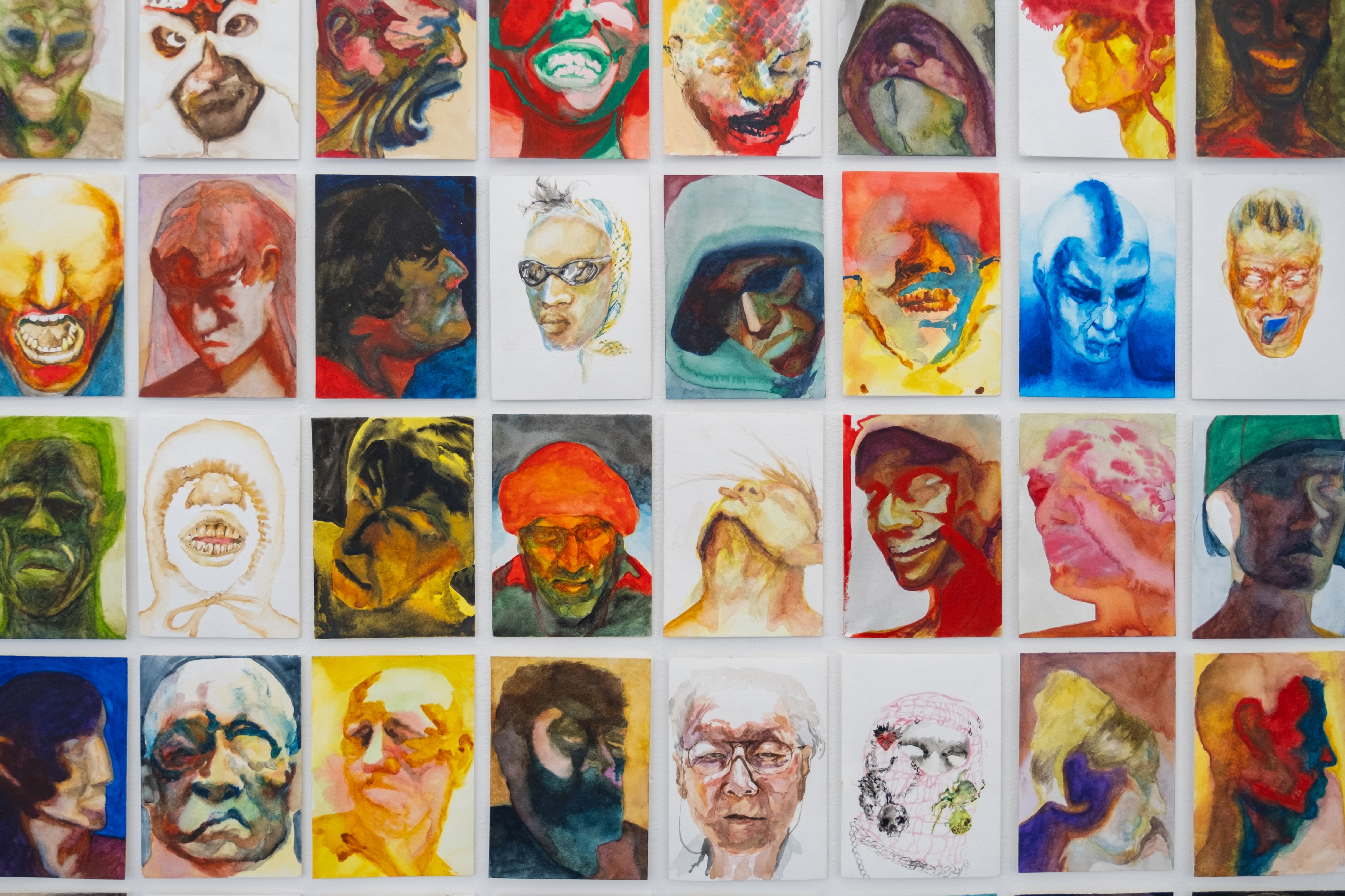 35 colorful watercolor portraits showing a variety of faces and emotions, arranged in a neat grid.