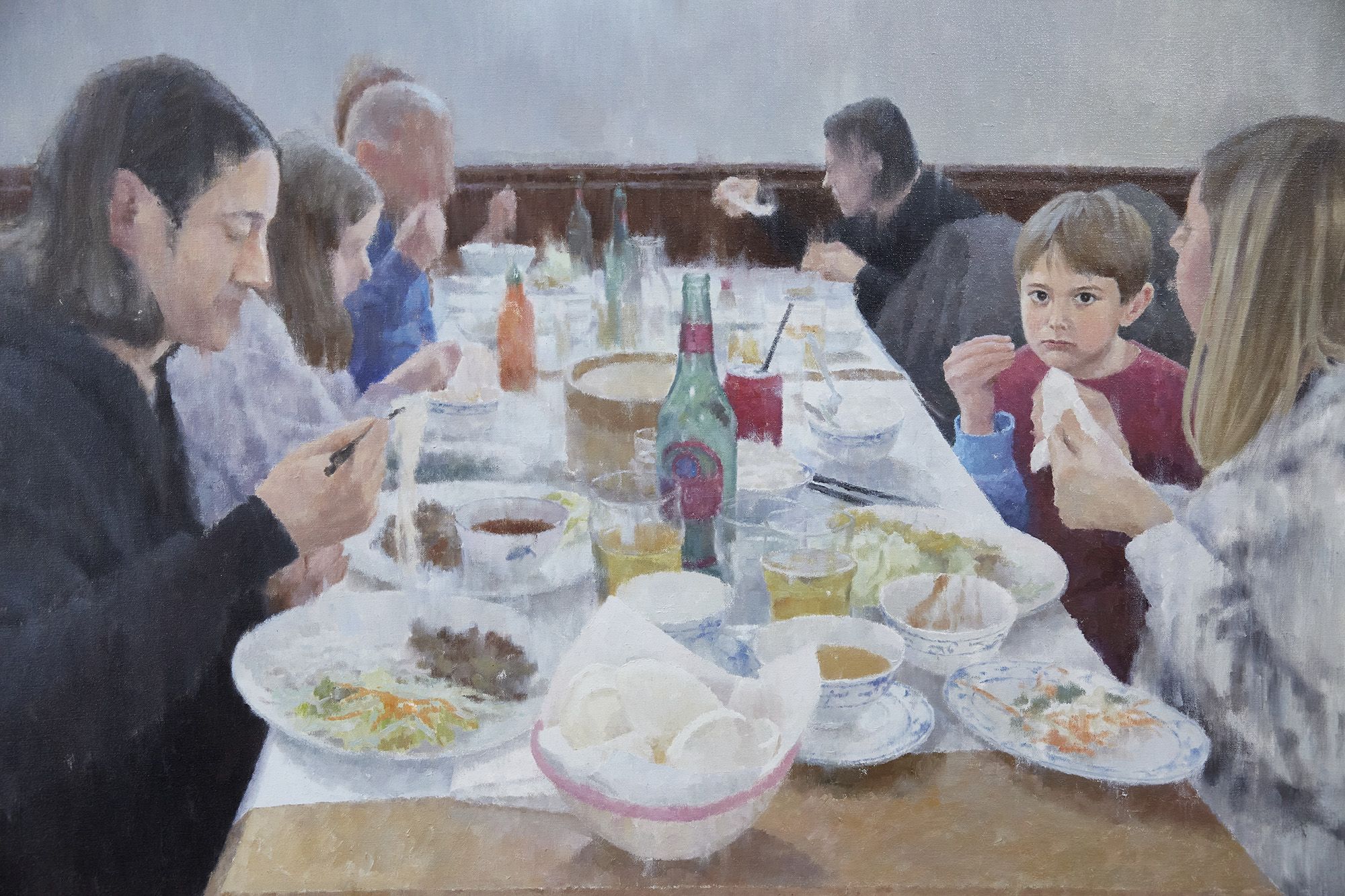 A painting of a group of people eating a meal at a table in a restaurant, a young boy is looking out at the viewer. 