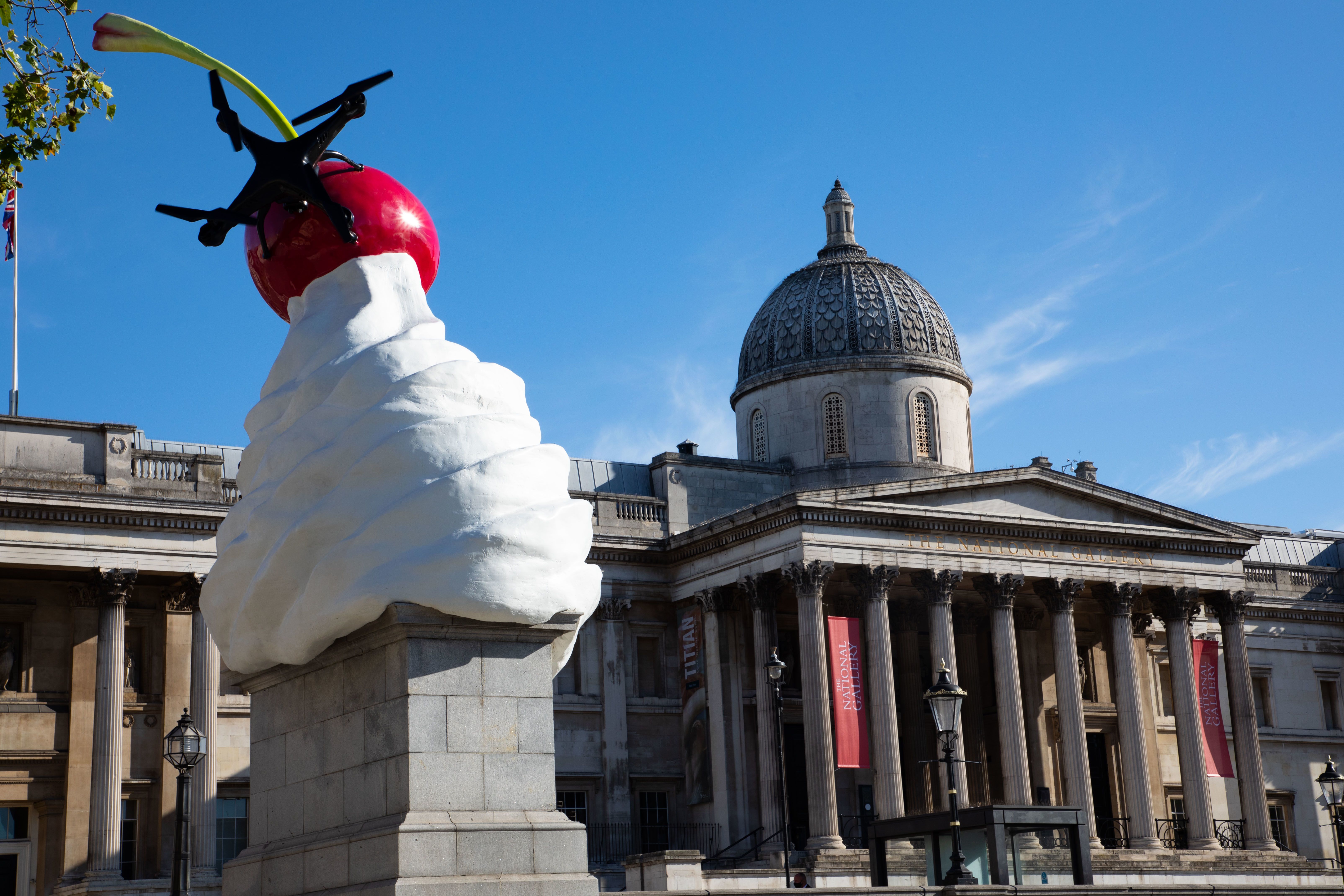 A sculpture of an ice cream with a cherry in it on top of a plinth in Trafalgar Square