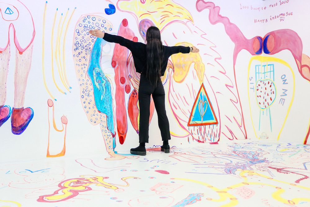 Jasmin Aldridge stands in front of a colourfully painted wall