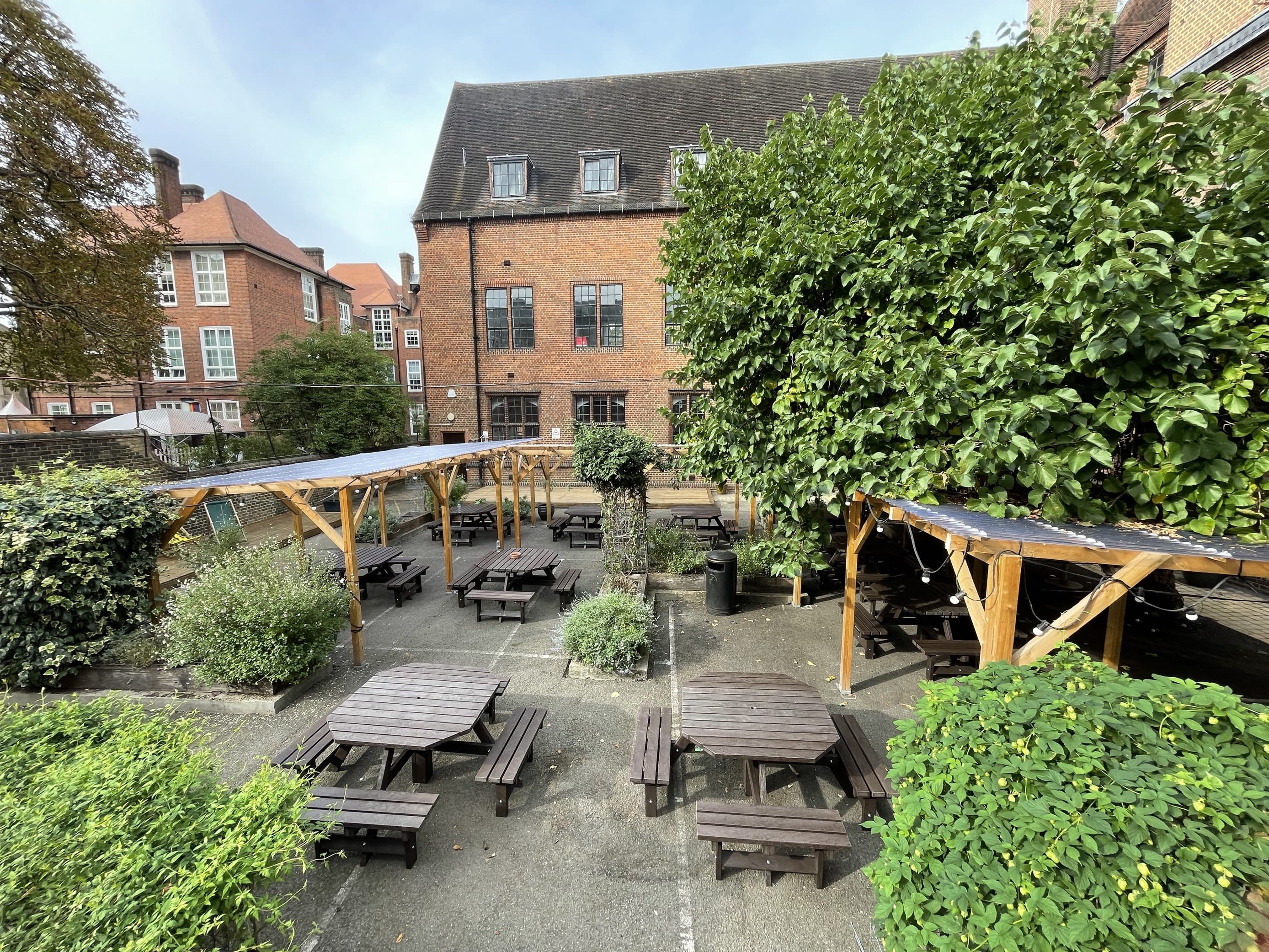 Full view of garden at Lime Grove, showing two wooden tables and seating and lots of trees.
