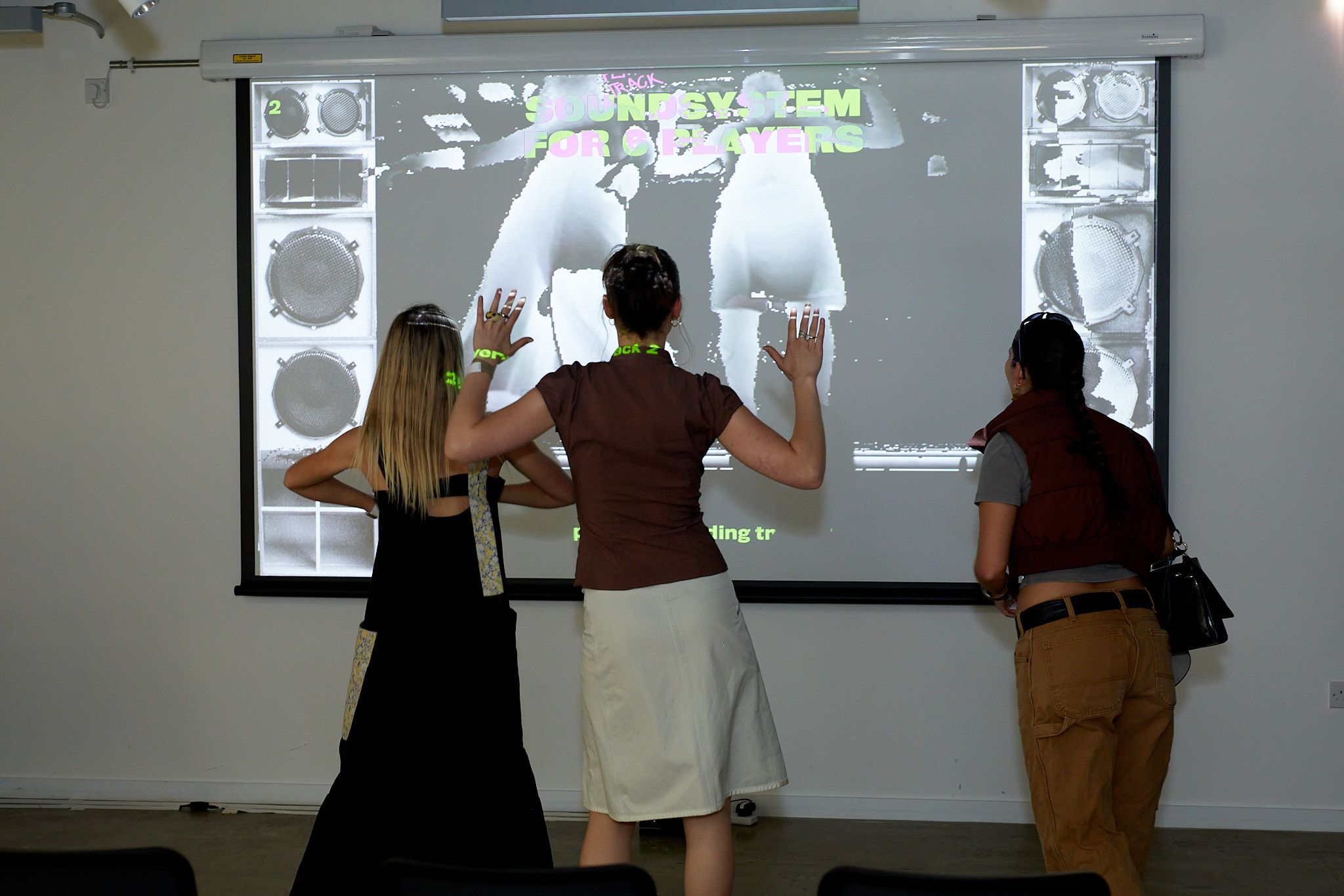 3 students stood in front of an interactive screen using AI.