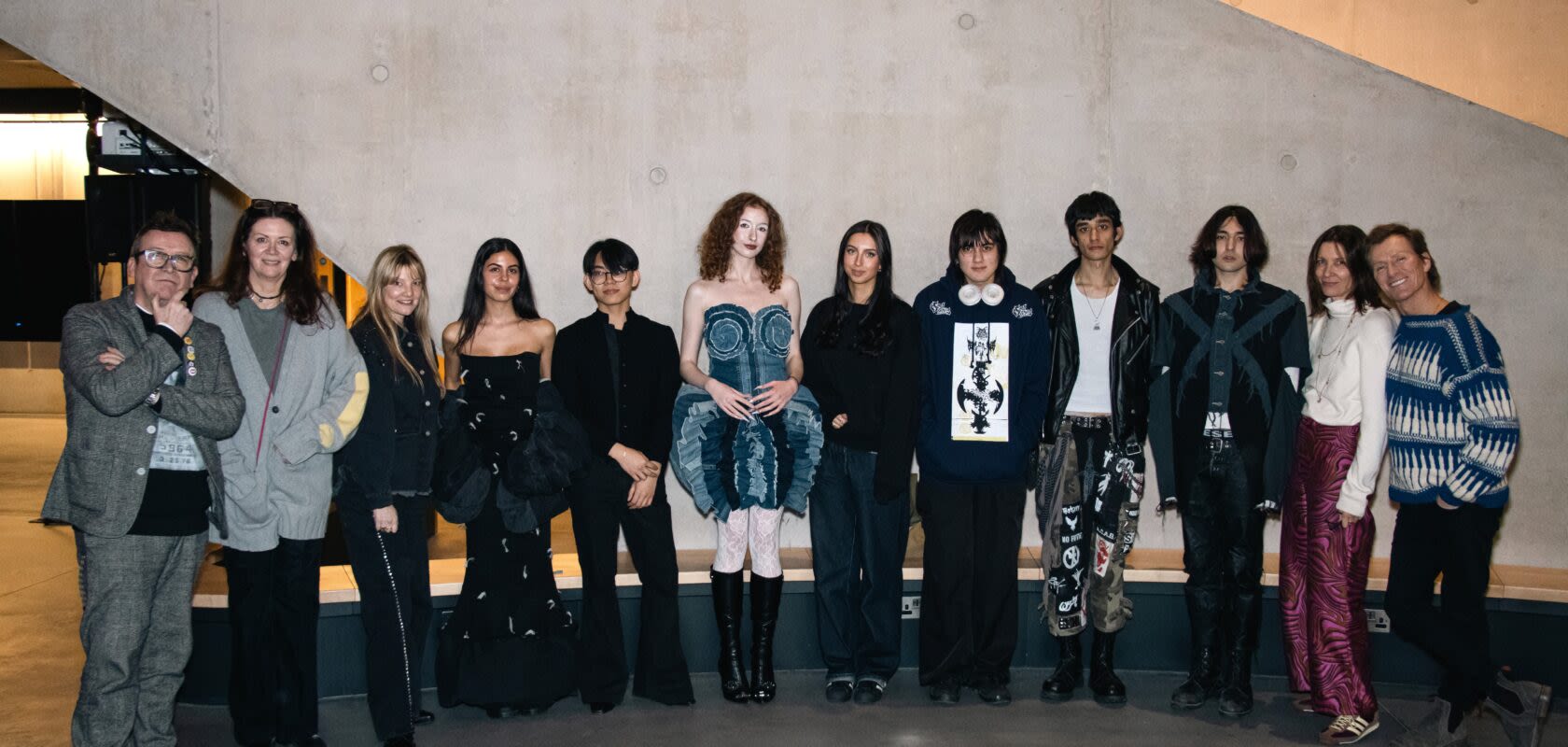 Several people standing in line wearing outfits made of denim. 