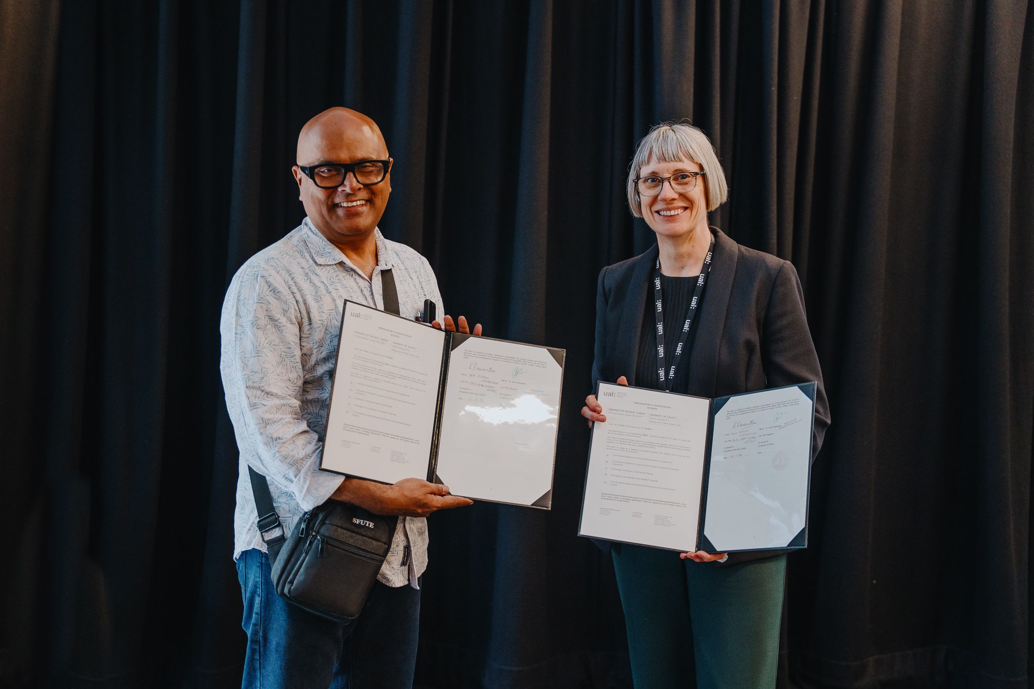 Two academics holding up a signed collaboration agreement