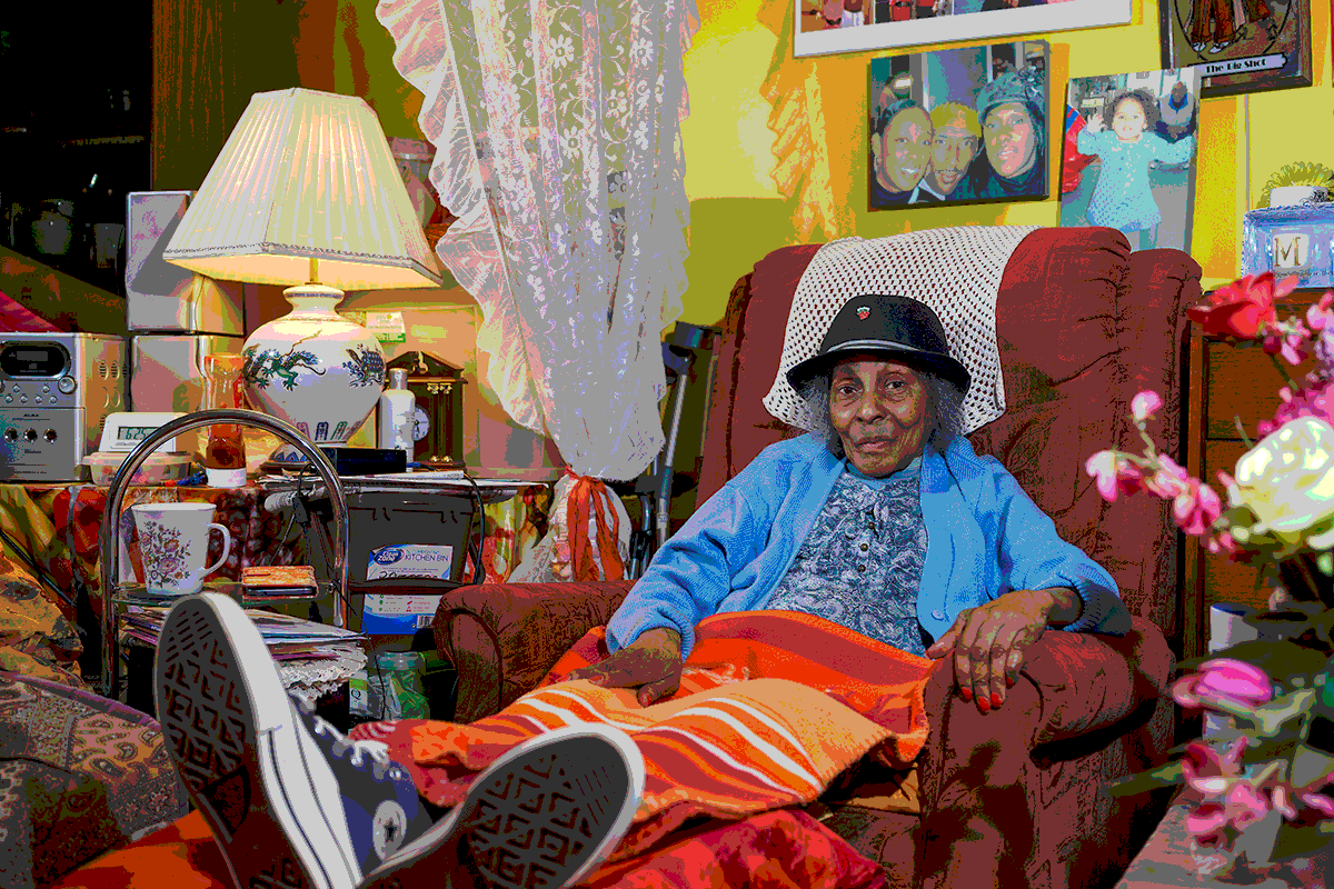 A woman sits in an armchair, surrounded by her living room.