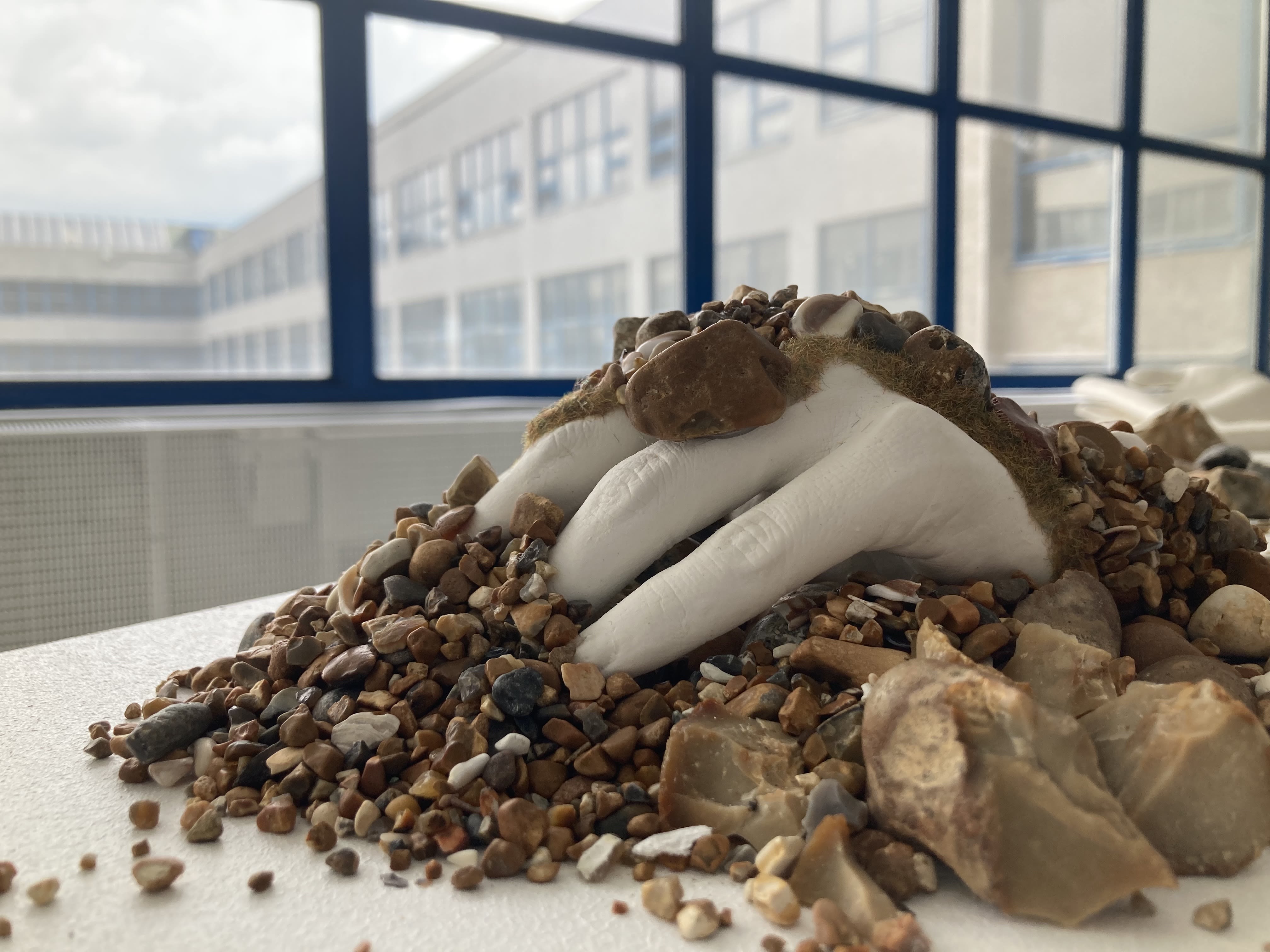 a sculpture of a hand covered in stones and pebbles