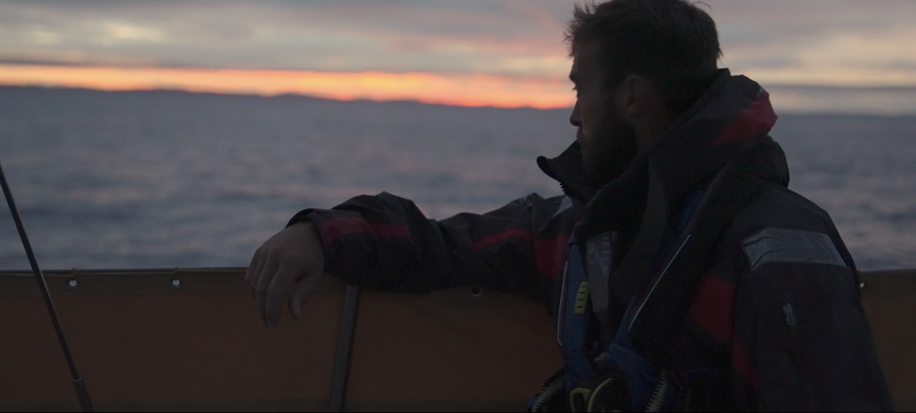 Person sat on boat with sunset in the horizon