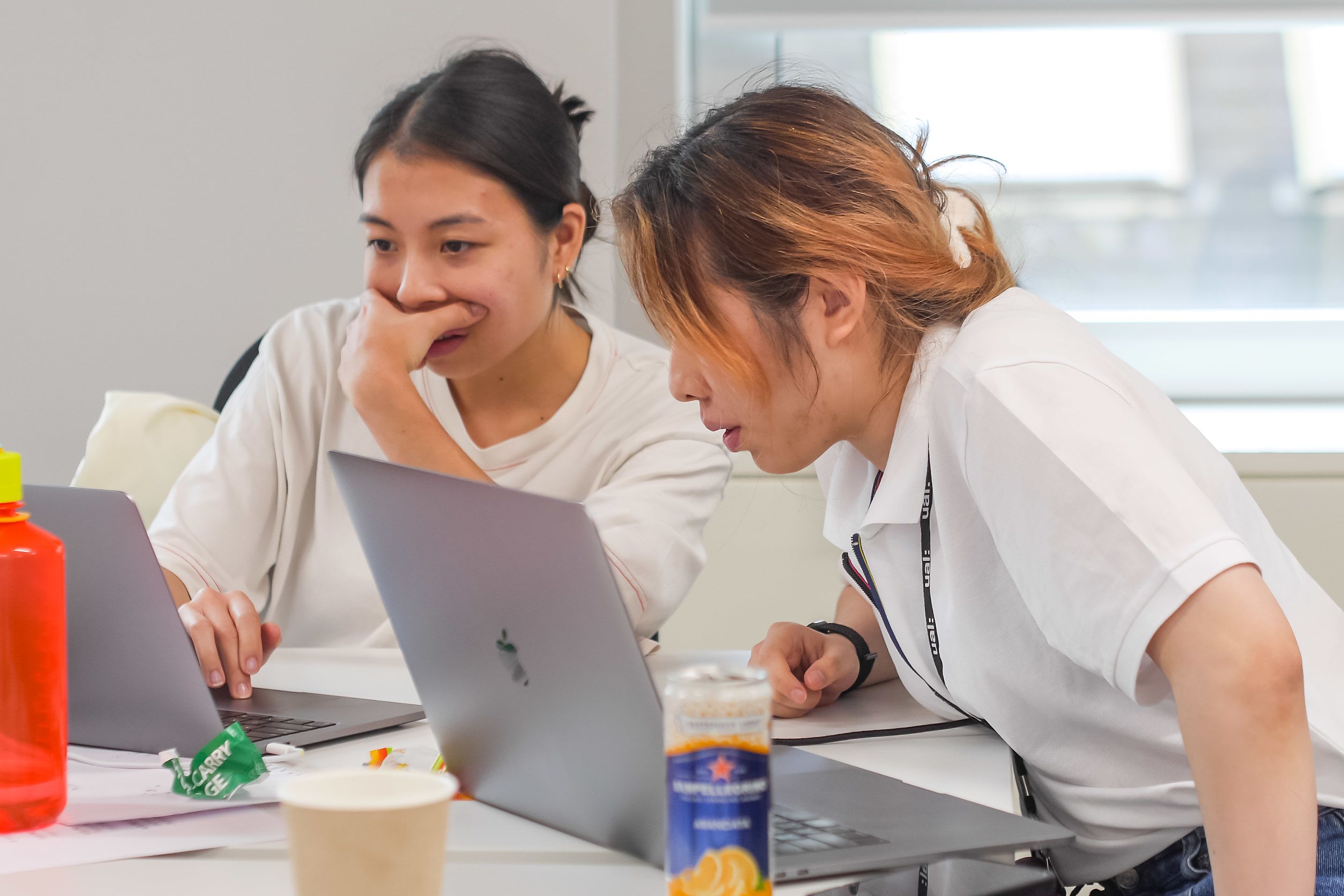 Two students sat on a desk working on a laptop 