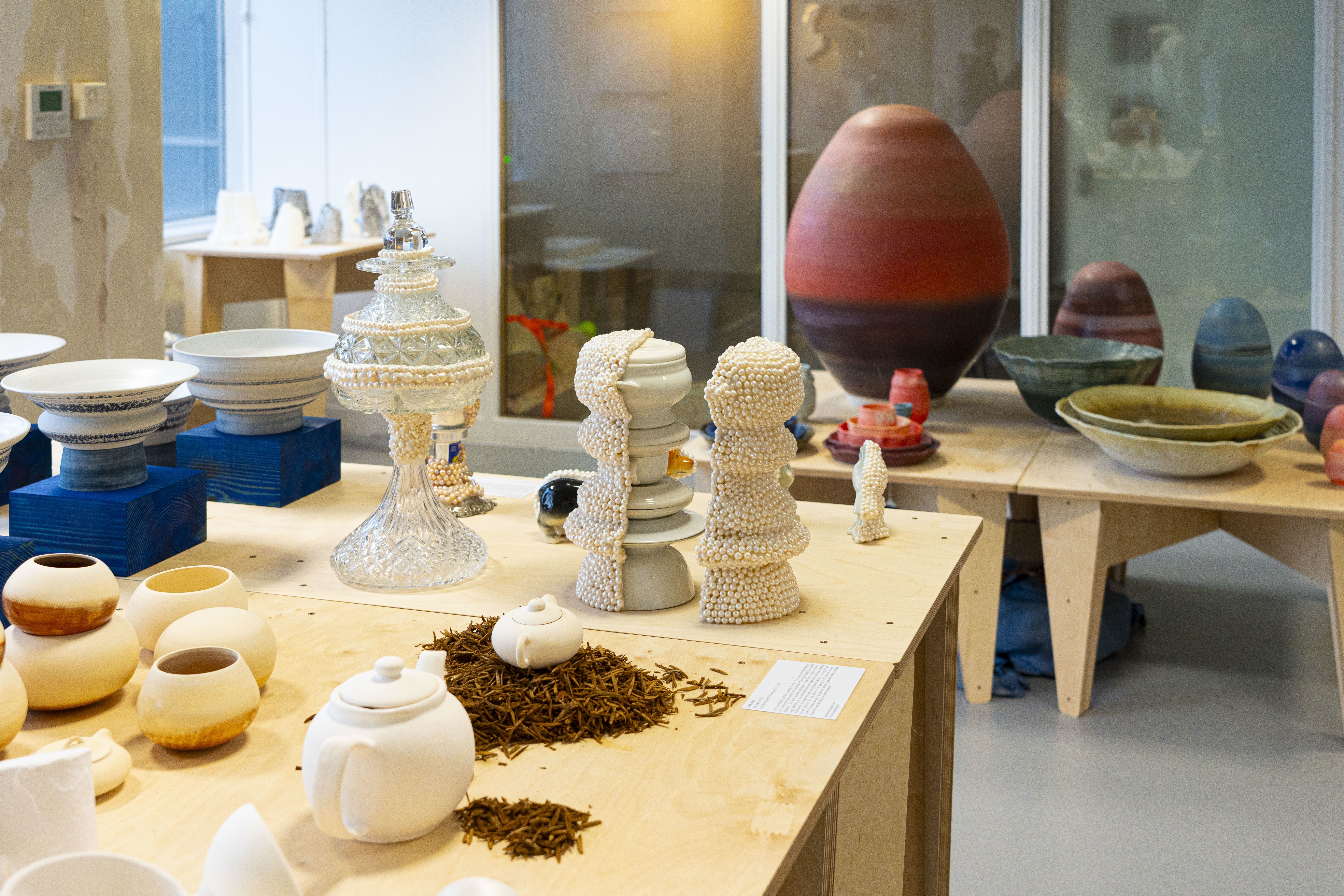 A shot of various ceramic artworks laid out on multiple tables